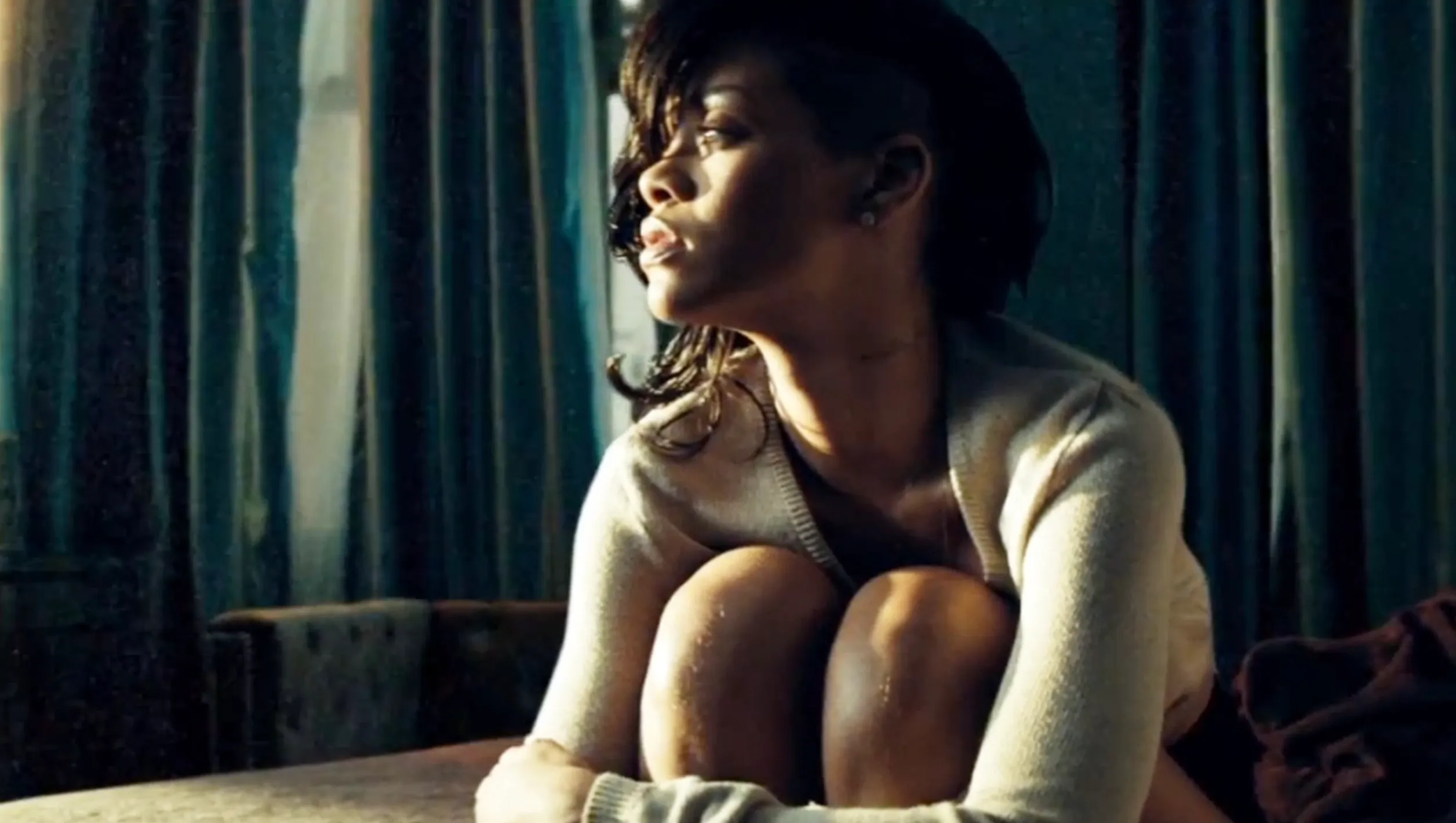 Rihanna, bathed in sunlight, looks pensive. Discover more in our Pop Culture A to Z Quiz.