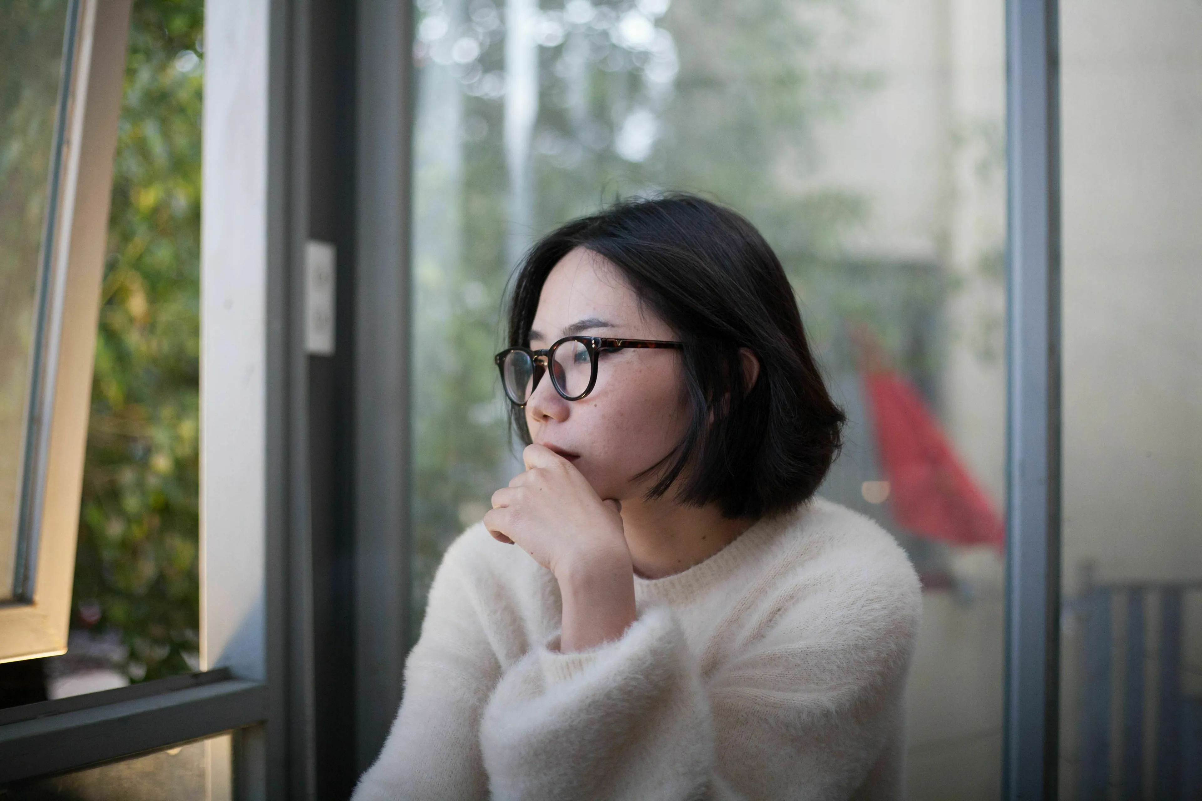 Woman in glasses and a white sweater, looking thoughtful. Test your pop culture quiz knowledge.