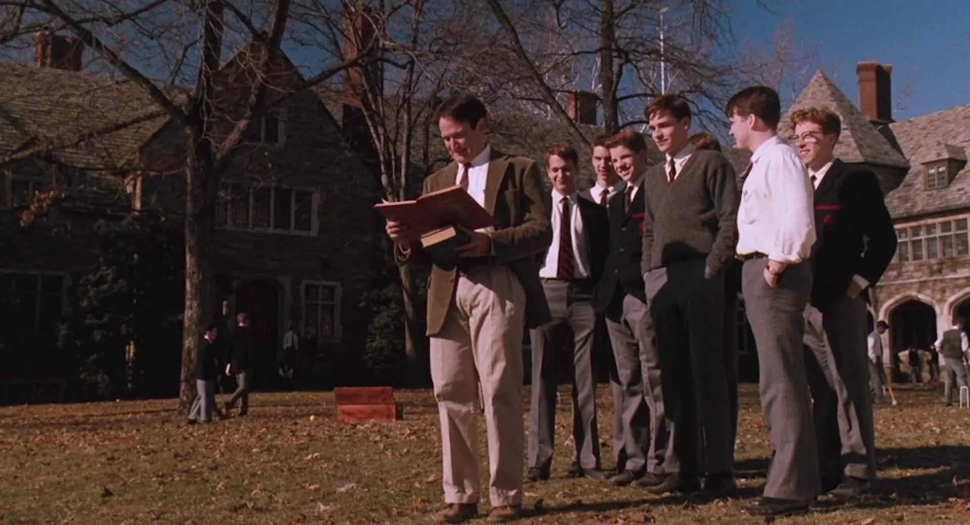 A man reads to students in a schoolyard, a scene from a movie for a Pop Culture Quiz.