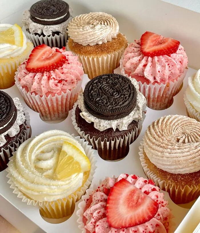 An assortment of cupcakes with various toppings like strawberries, Oreos, and lemon slices, amazing treats by bakers.