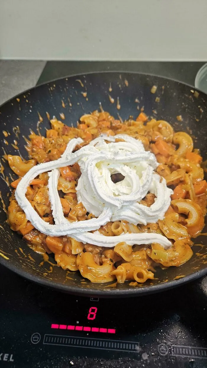 A pan of pasta topped with whipped cream as a questionable food combo served on a plate.