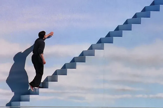 Truman Burbank ascends a flight of stairs toward a painted sky, a moment from The Truman Show for a movie night.