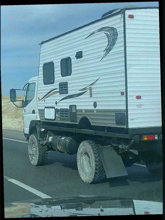 A large white RV trailer attached to an off-road truck, an example of turning junk into clever solutions.