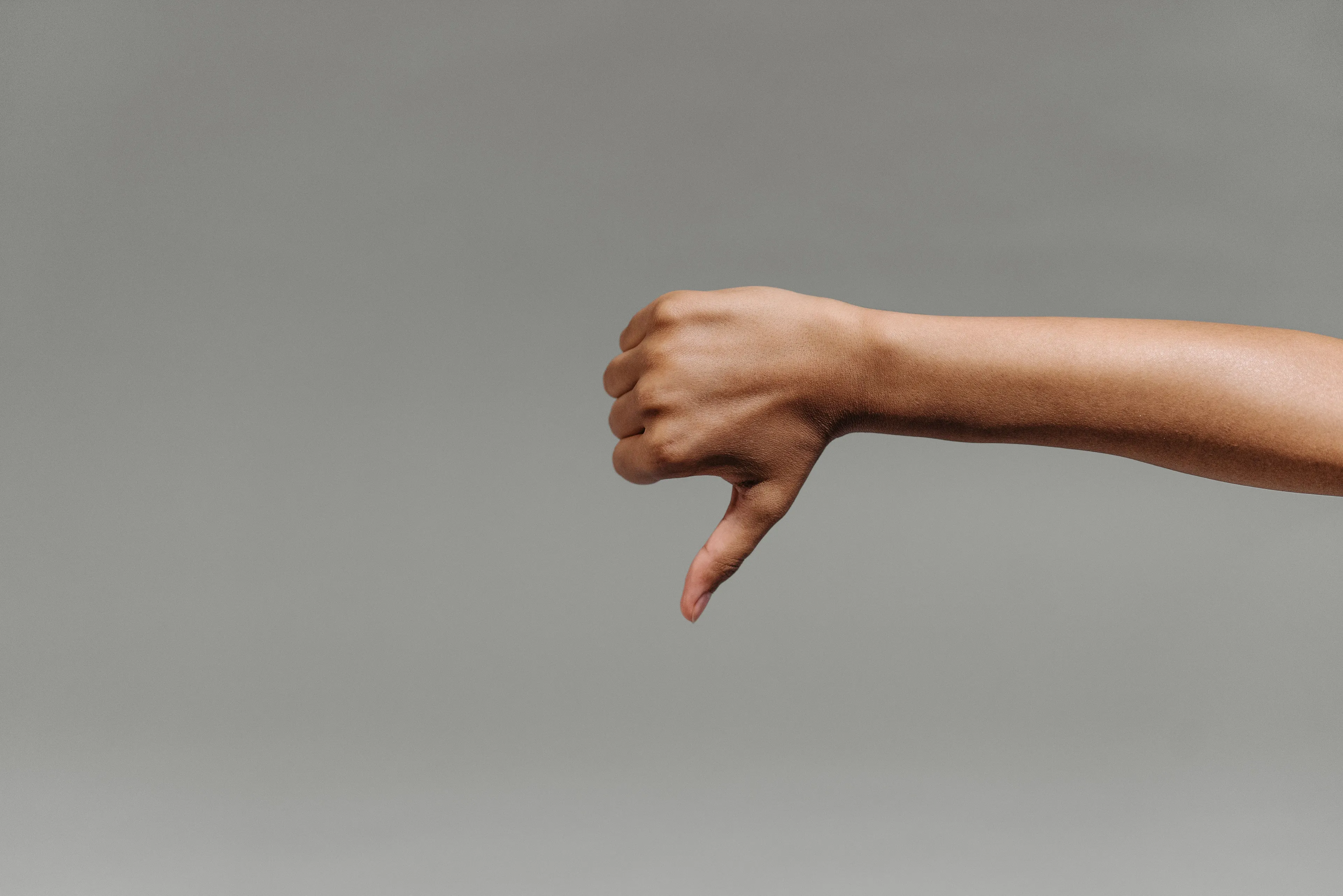 A hand gives a thumbs down, representing the fear of mediocrity and not being good enough.