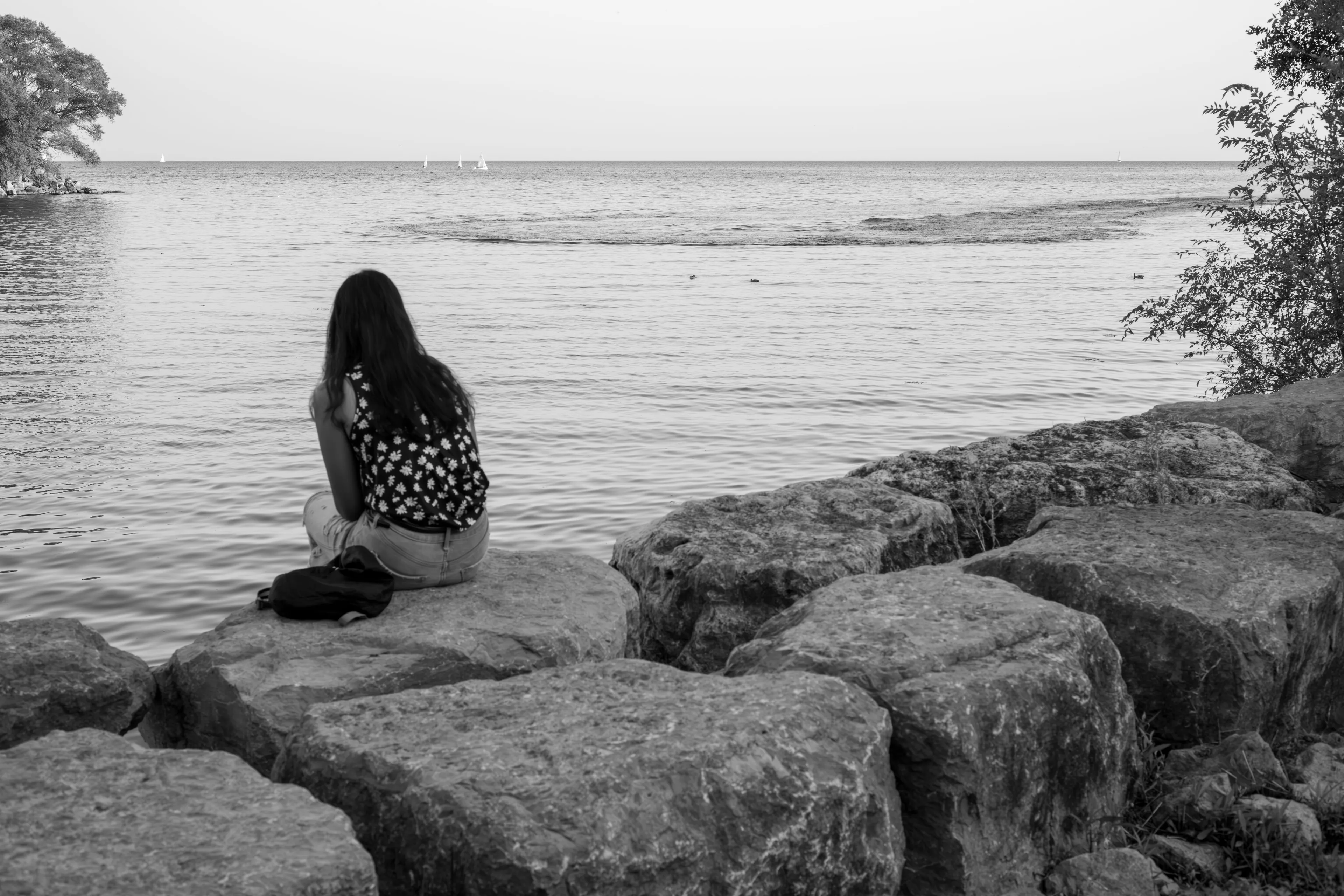 A lone woman sitting on rocks by a lake, illustrating the fear of abandonment.
