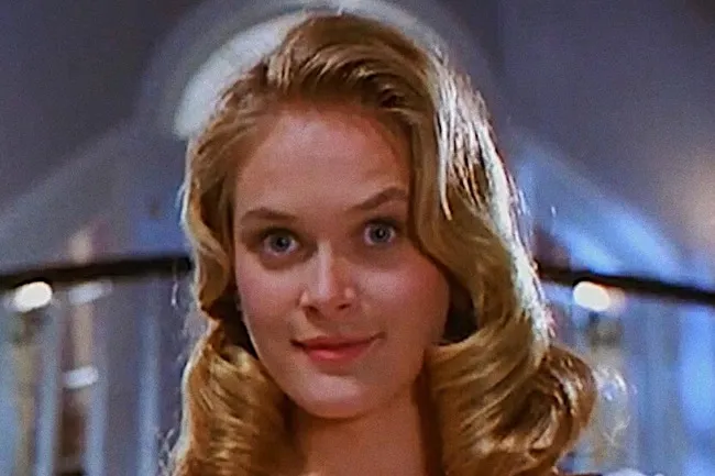 Cher Horowitz, a blonde woman with blue eyes and an updo, smiles at the viewer.