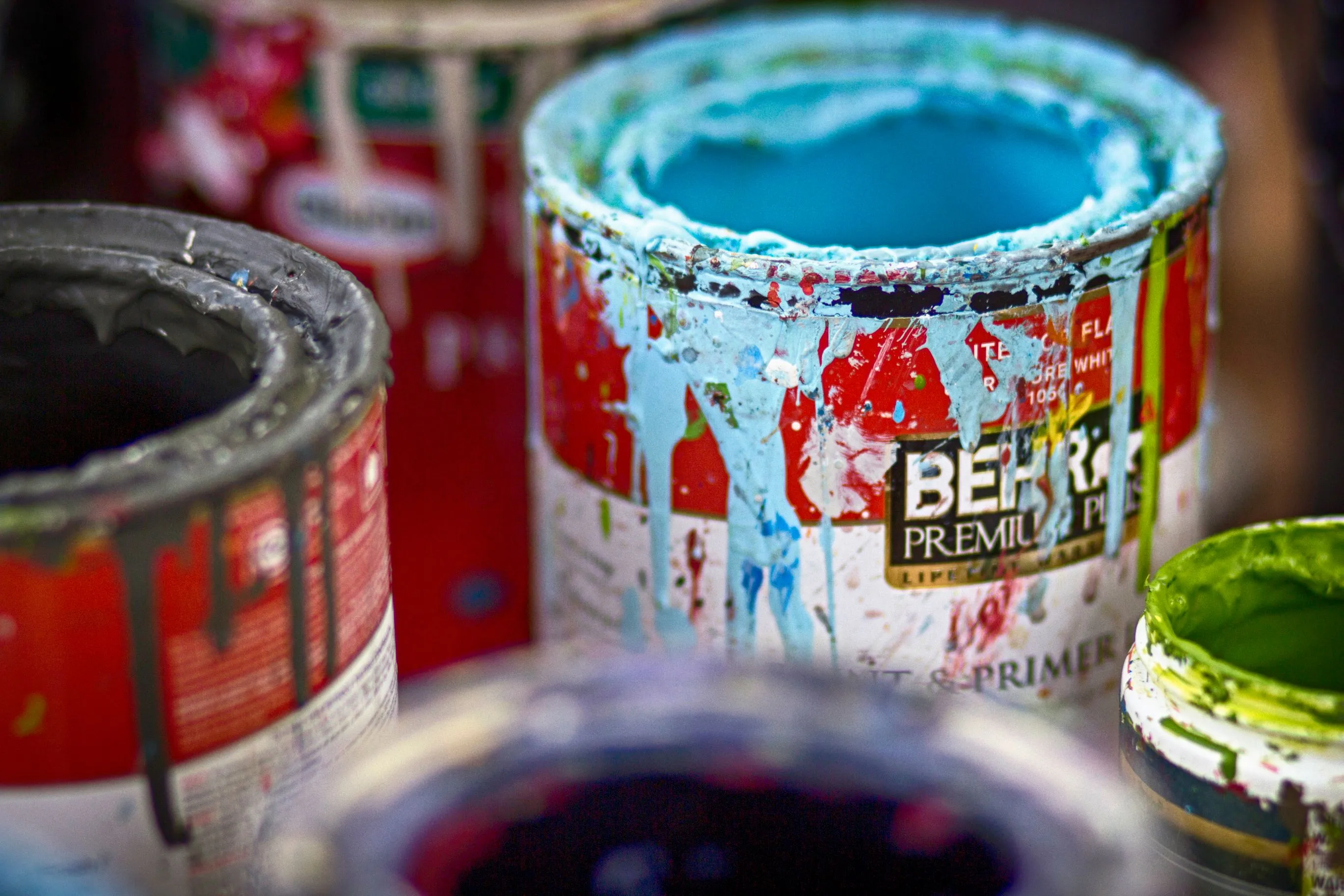 A close-up of several cans of spilled paint, including a light blue can, evoking the smell of loneliness.