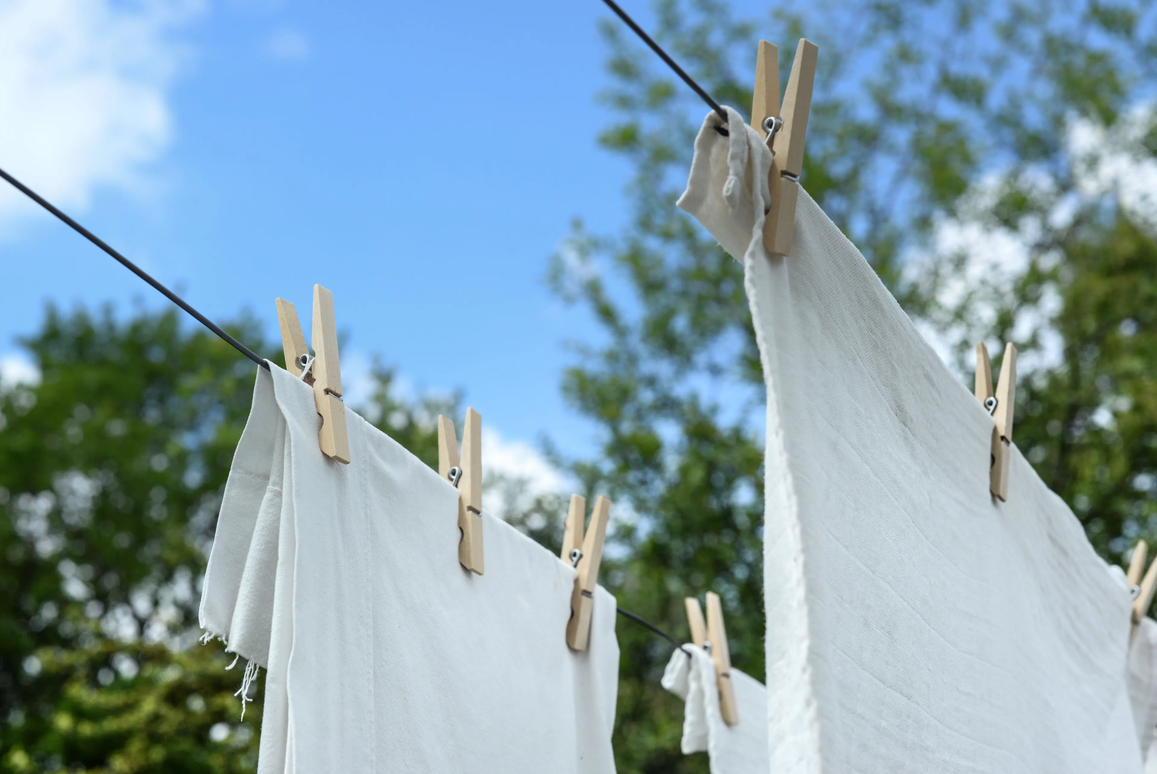 White fresh linen drying on a clothesline against a blue sky, suggesting the smell of loneliness.