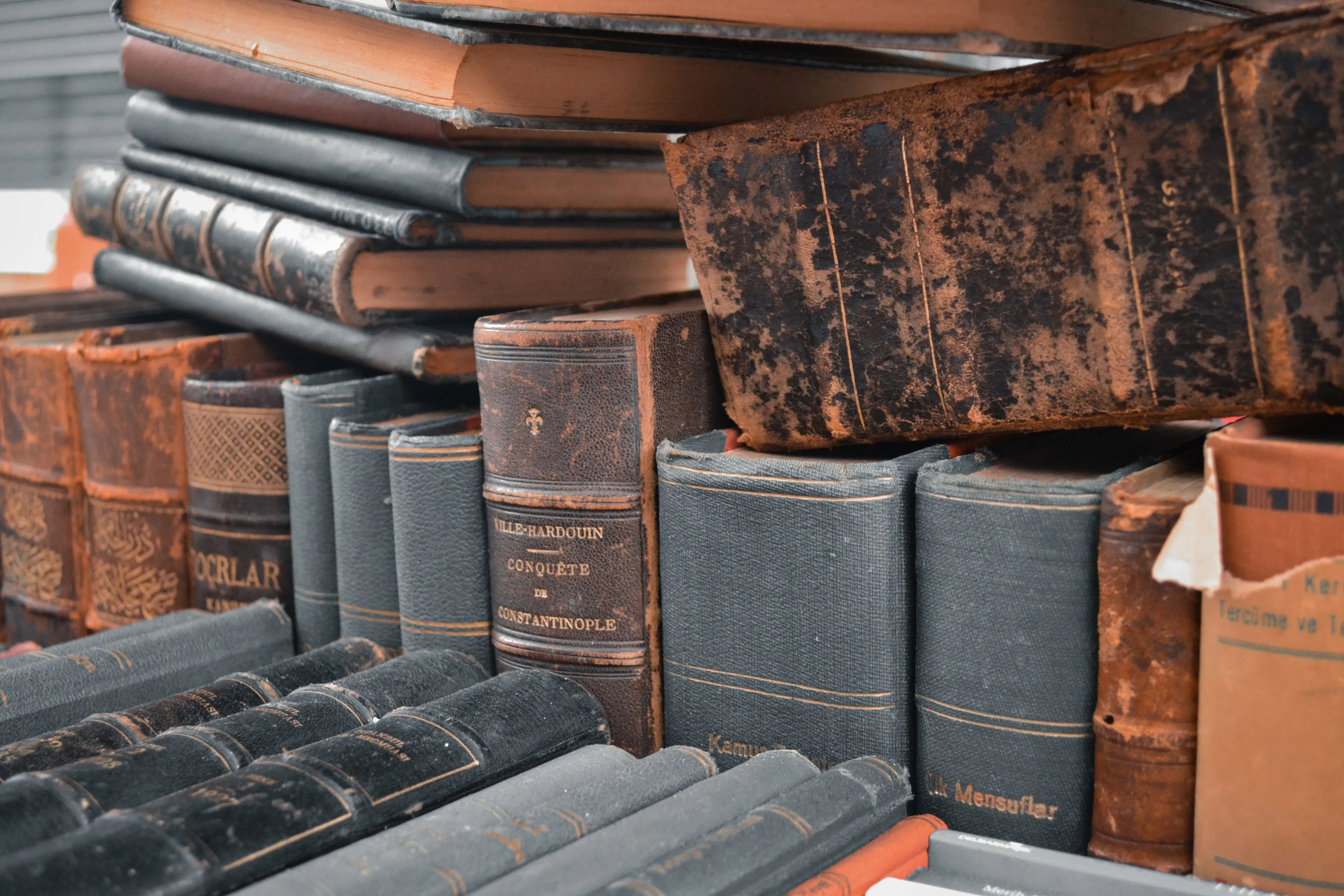 A stack of old books with weathered covers, representing the distinct smell of loneliness.