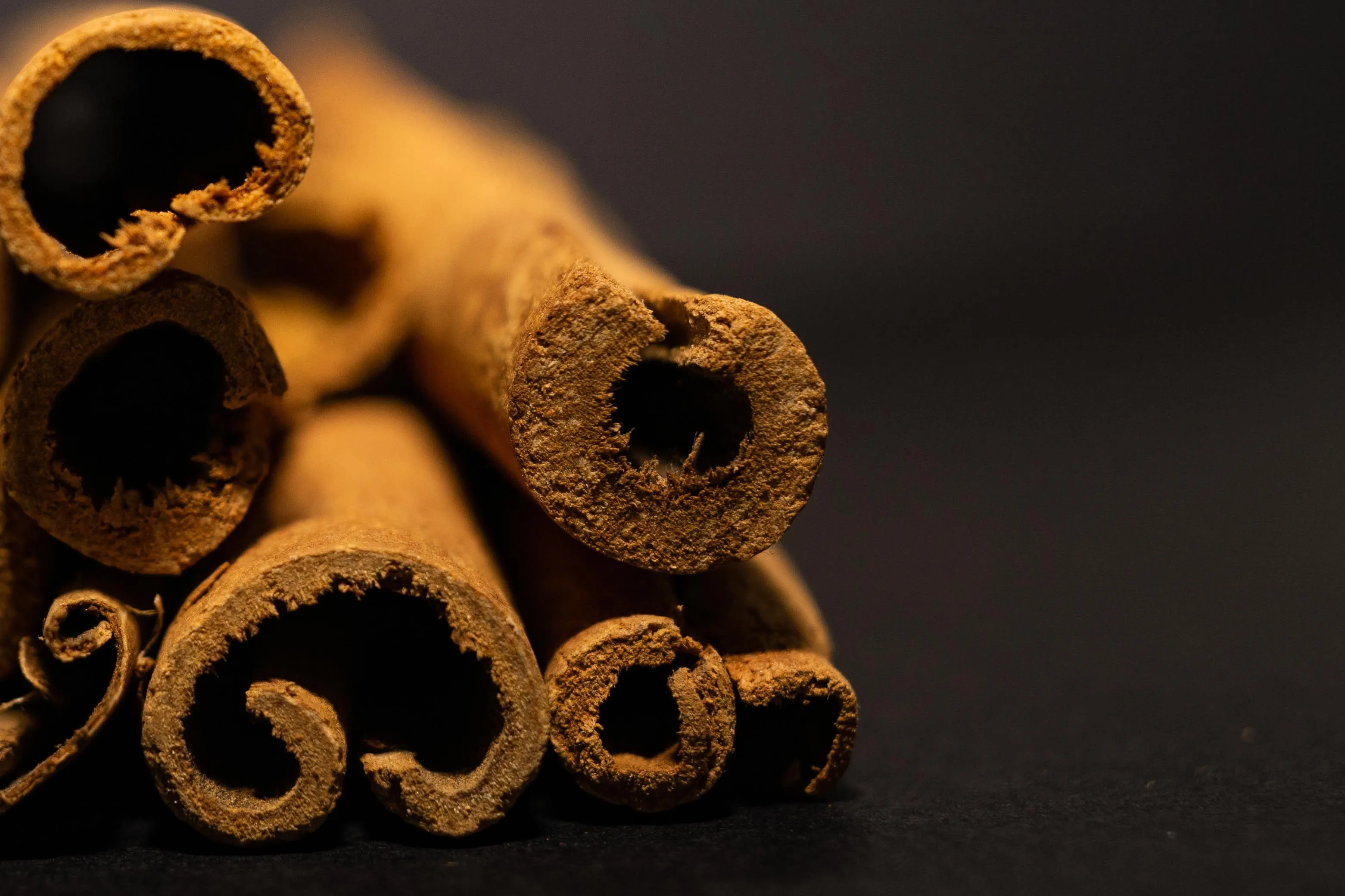 A tightly packed bundle of cinnamon sticks on a dark background, representing the smell of loneliness.