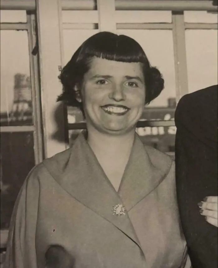 A smiling woman with an unfortunate short bob haircut and very short bangs.
