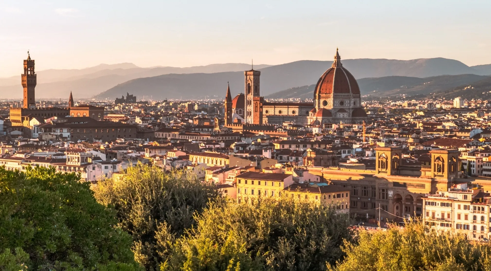 Panoramic view of Florence, birthplace of the Renaissance, with iconic domed cathedrals and historic buildings at sunset.