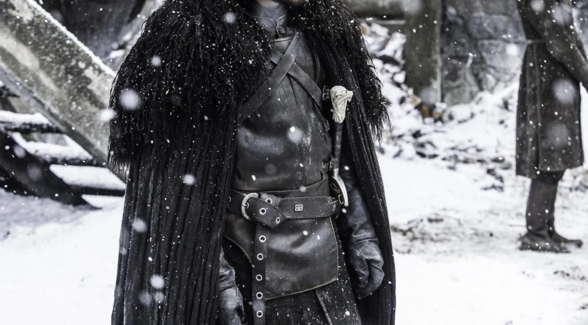 Jon Snow from Game of Thrones in a fur cloak and leather attire standing in snow. Popular TV show outfit.