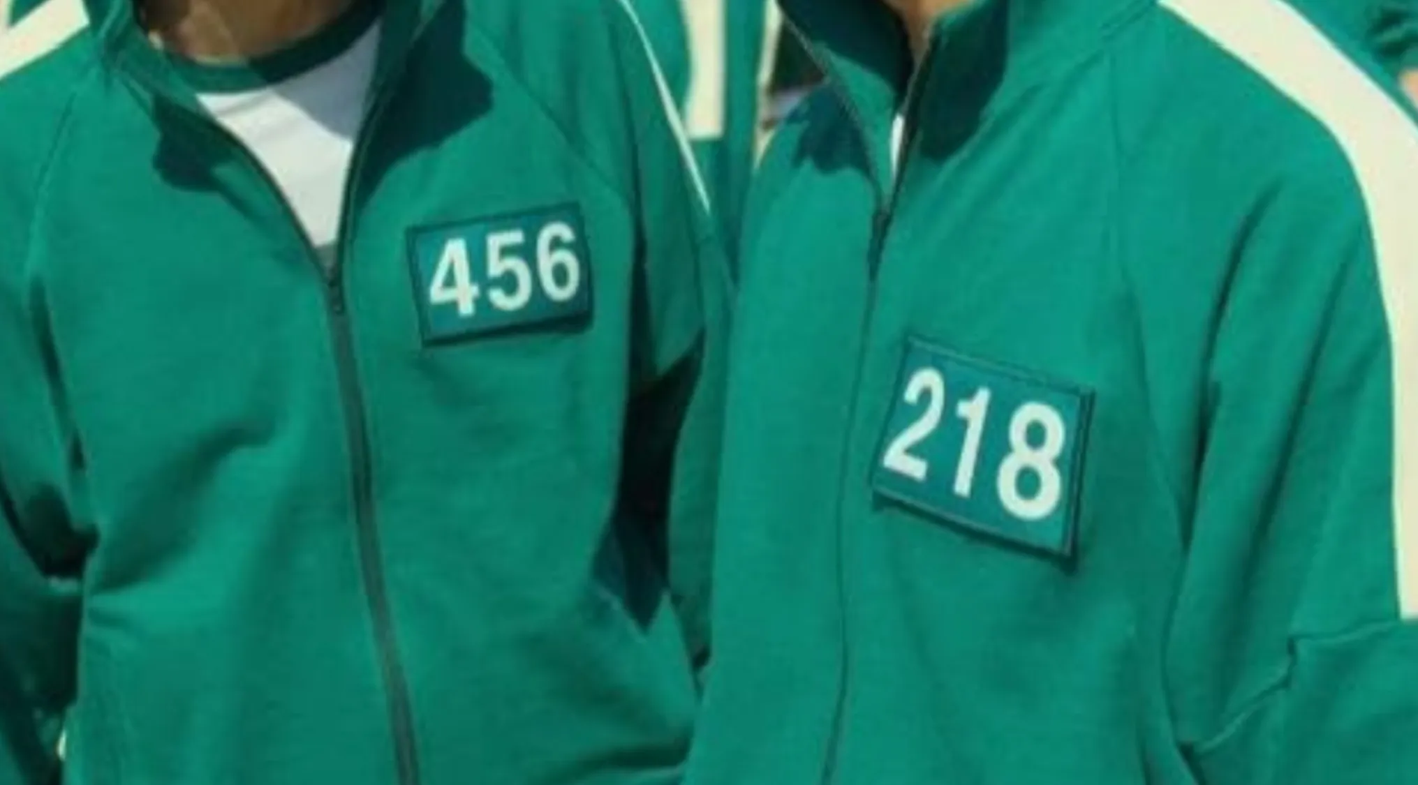 Close-up of two characters wearing green tracksuits with numbers 456 and 218, highlighting popular TV show outfits.