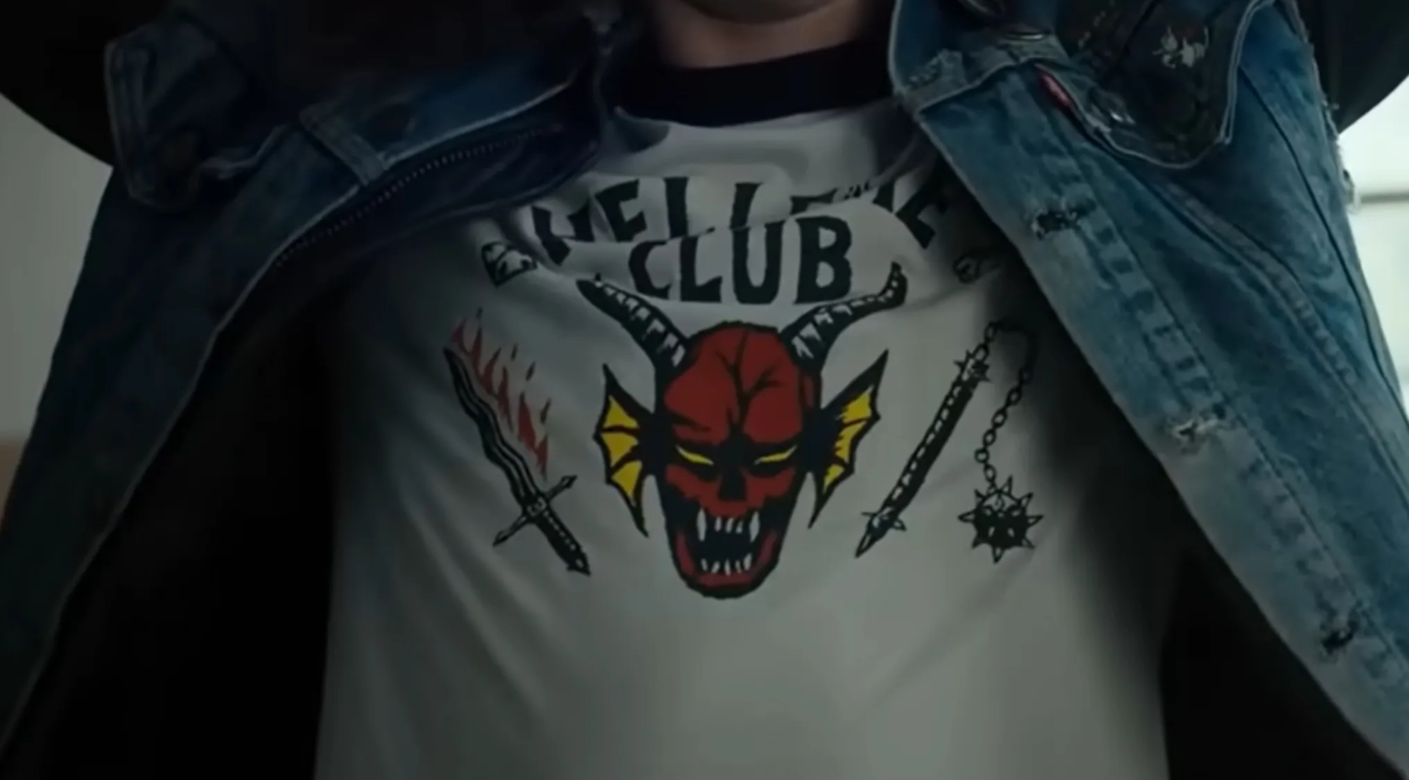Close-up of a Hellfire Club shirt, an iconic TV show outfit, visible under a denim jacket.