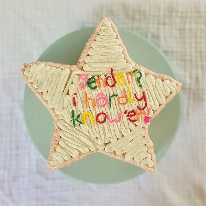 A star-shaped baker's treat cake with colorful icing that reads 'Gender? I hardly know 'em!'