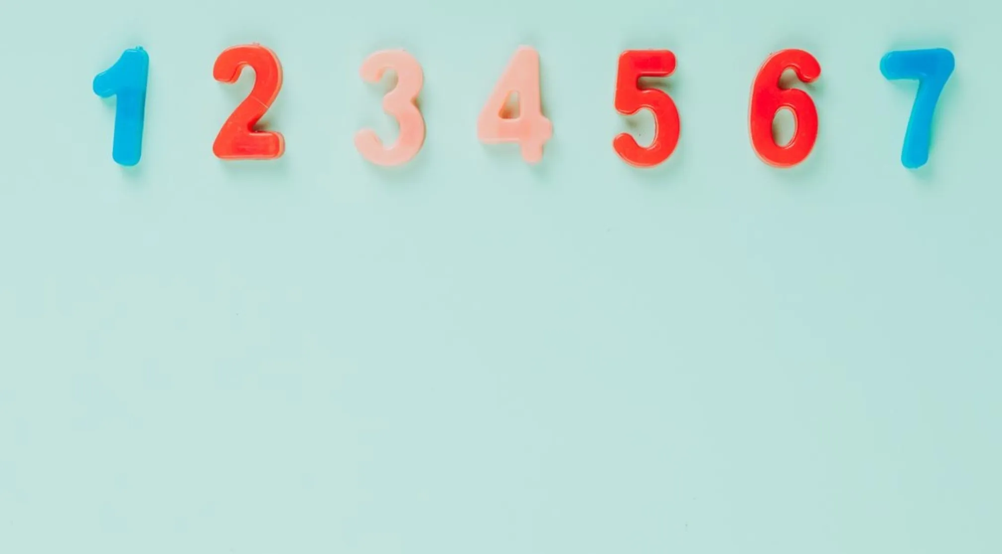 Basic Math: Colorful plastic numbers 1 through 7 in a row on a light blue background.