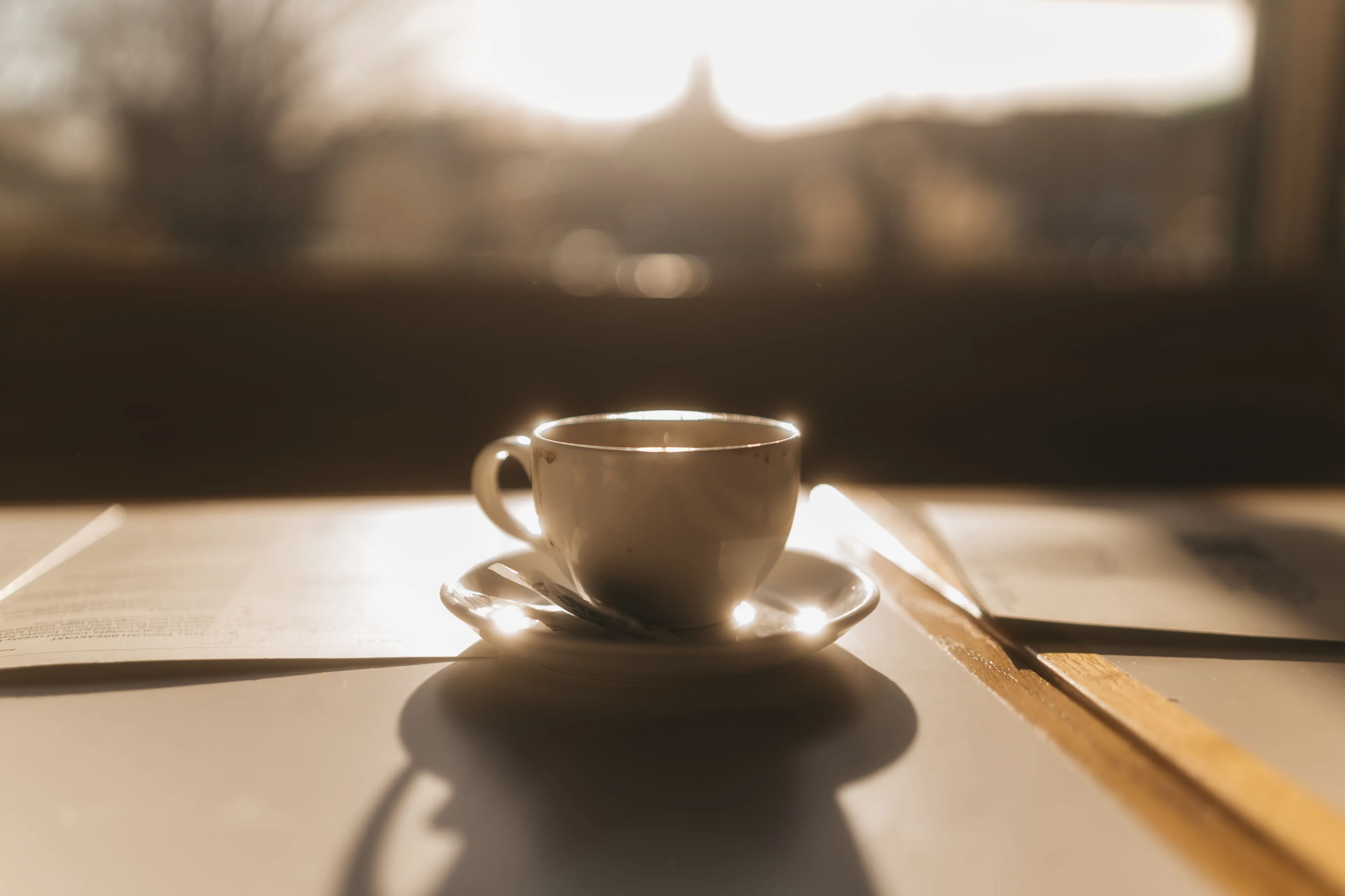 A slow cup of coffee, gleaming in sunlight, on a table. Ideal Saturday morning scene with a warm, inviting glow.