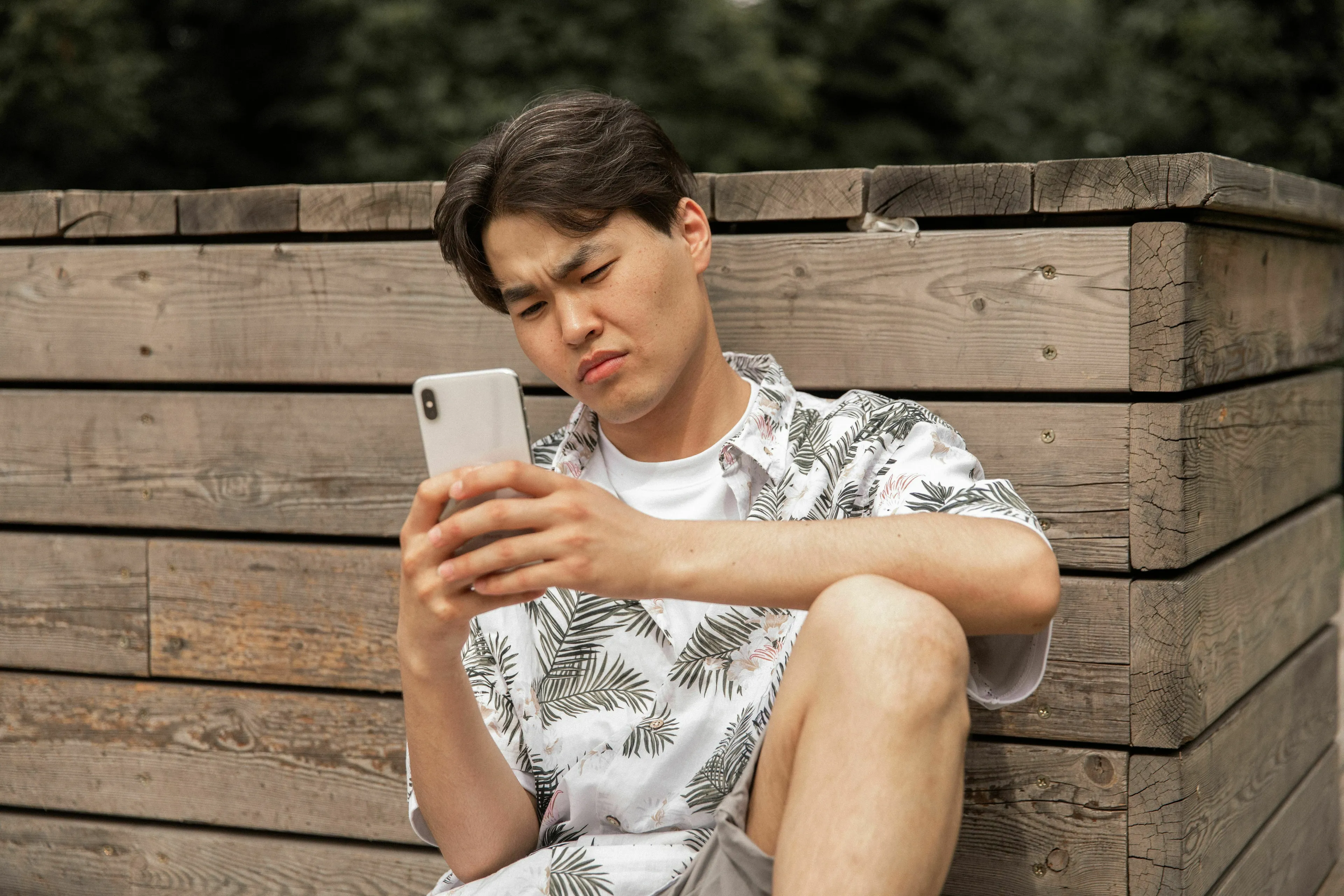 A young man looks confused at his phone, posing the question: What's your red flag when dating cancels plans last minute?