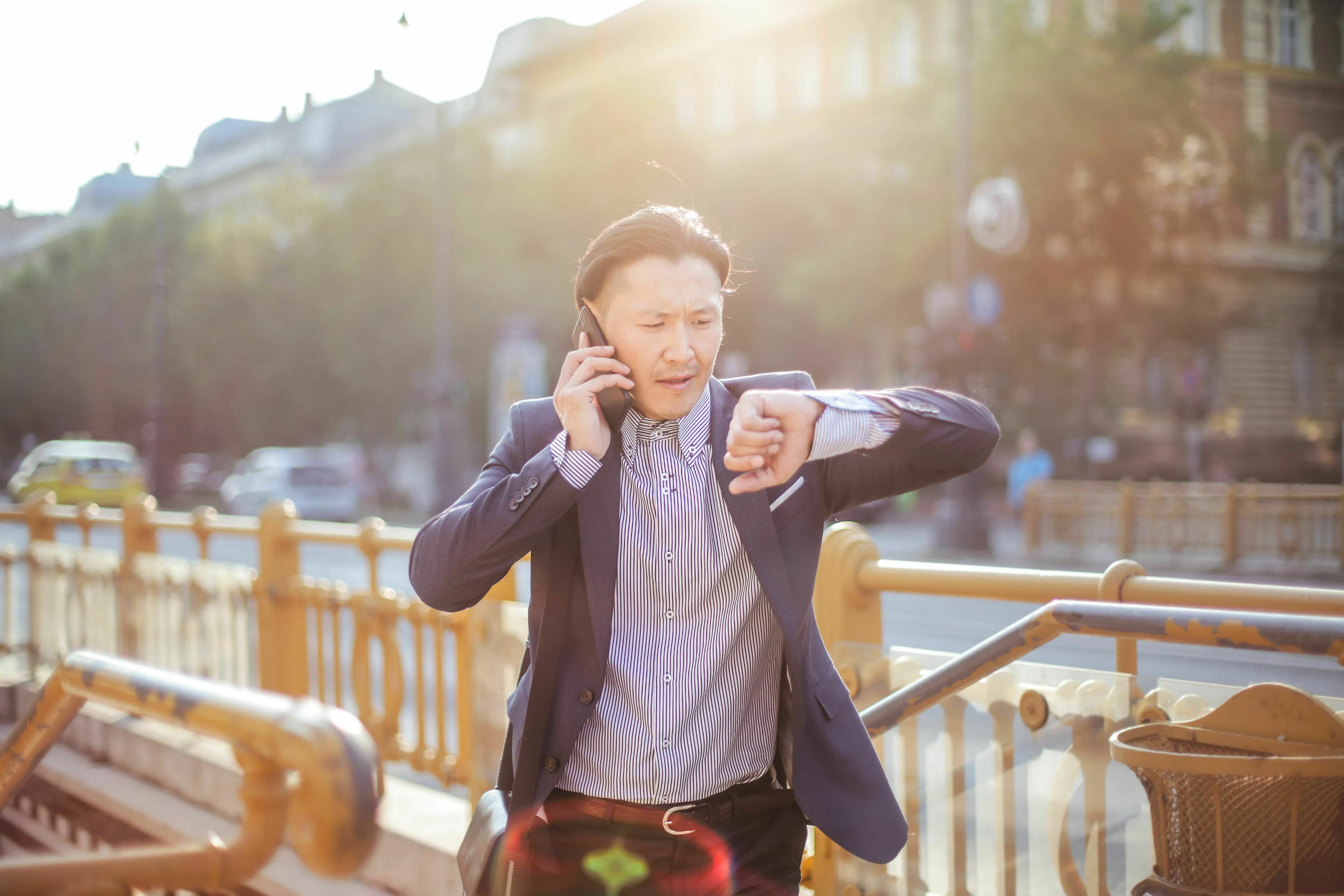 A man in a suit jacket, talking on a phone and checking his watch with concern, highlights a red flag scenario.