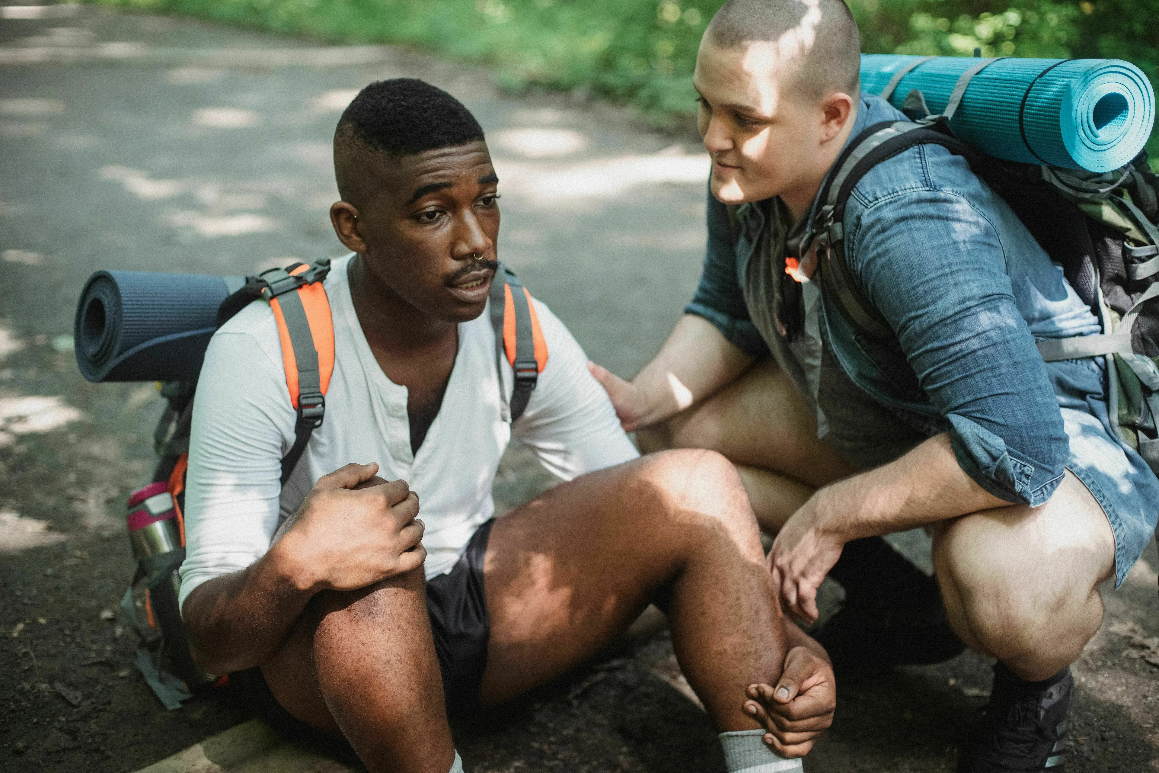 Two hikers, one sitting with a troubled expression and another kneeling beside him, illustrating a red flag moment.