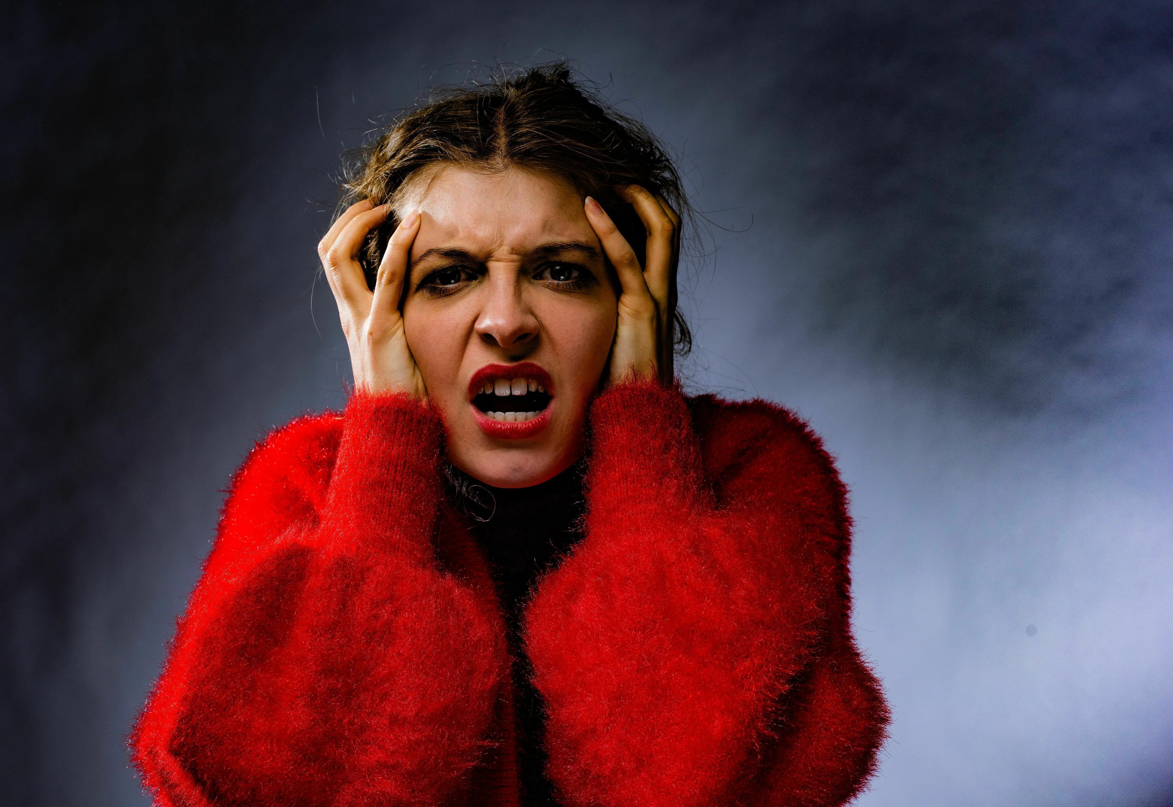 A distressed woman in a red fuzzy sweater holds her head. She has a bad decision to confront. What is your red flag?