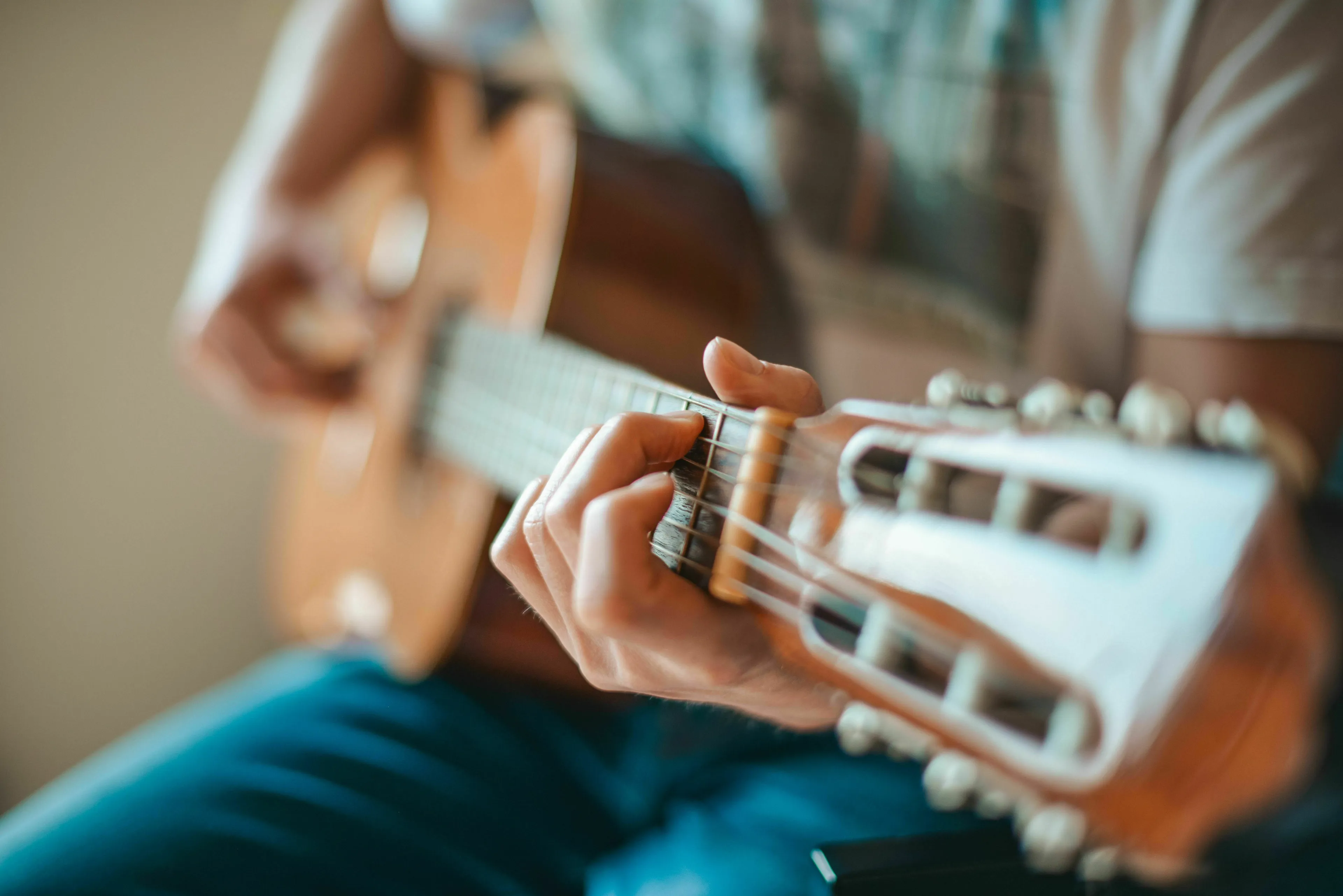 Close-up of a person's hands playing an acoustic guitar, focusing on the fretboard. This reminds me of a musical scale question for general knowledge.