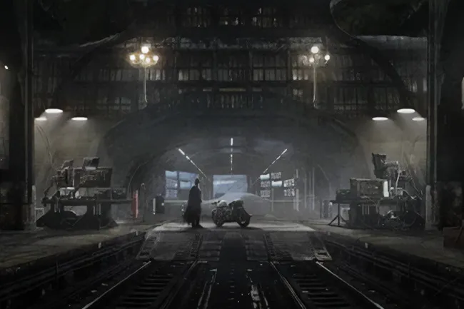 A dark, cavernous space with a figure next to a motorcycle, reminiscent of Batman's cave or a secret lair.