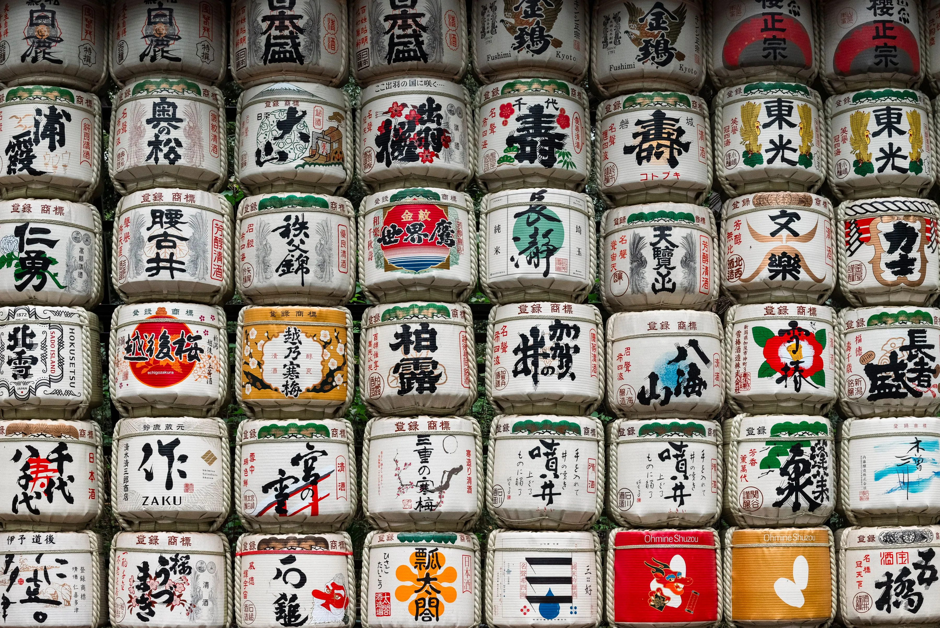 Wall of decorated traditional sake barrels, showcasing the primary ingredient in Japanese sake. General Knowledge.
