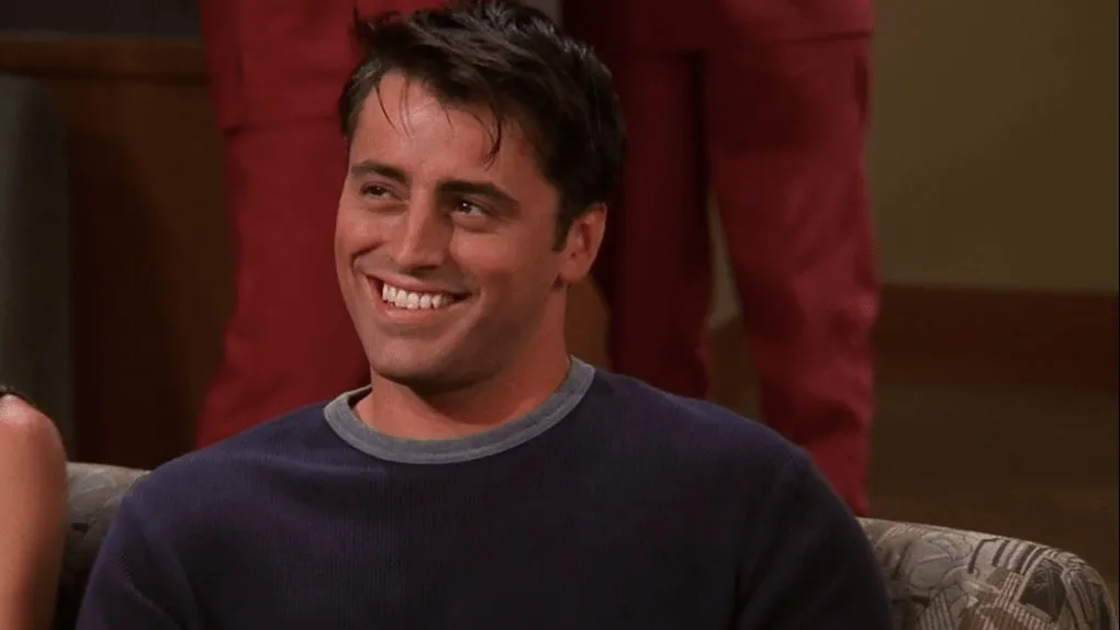 Joey Tribbiani smiling, embodying the TV catchphrase "How you doin'?" in a playful, confident manner.