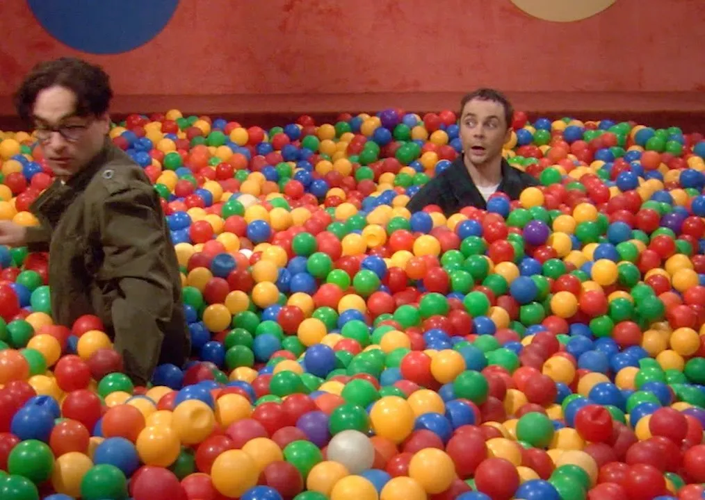 Leonard and Sheldon submerged in a colorful ball pit. Sheldon's surprised expression could mean, "Bazinga!"