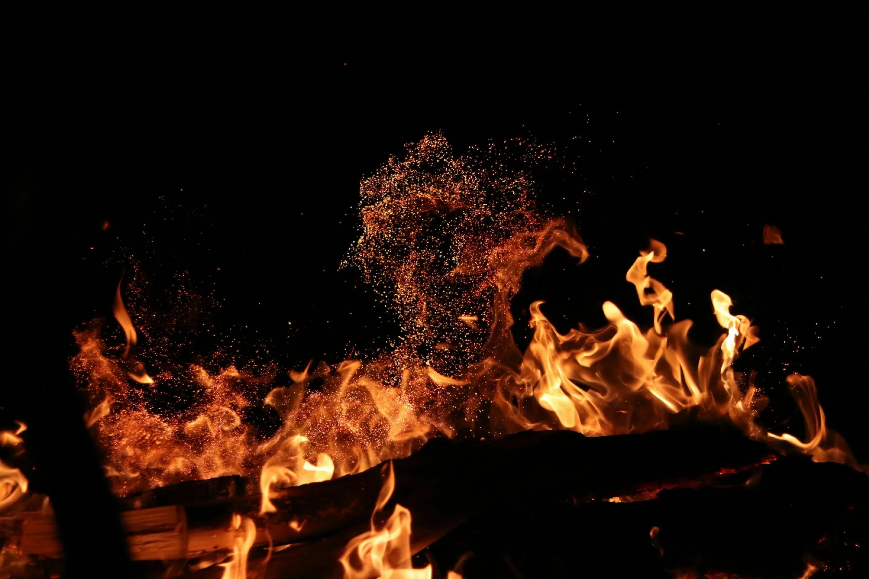 Bright orange flames and sparks rise from burning wood against a dark background, representing exothermic reactions for a general knowledge test.