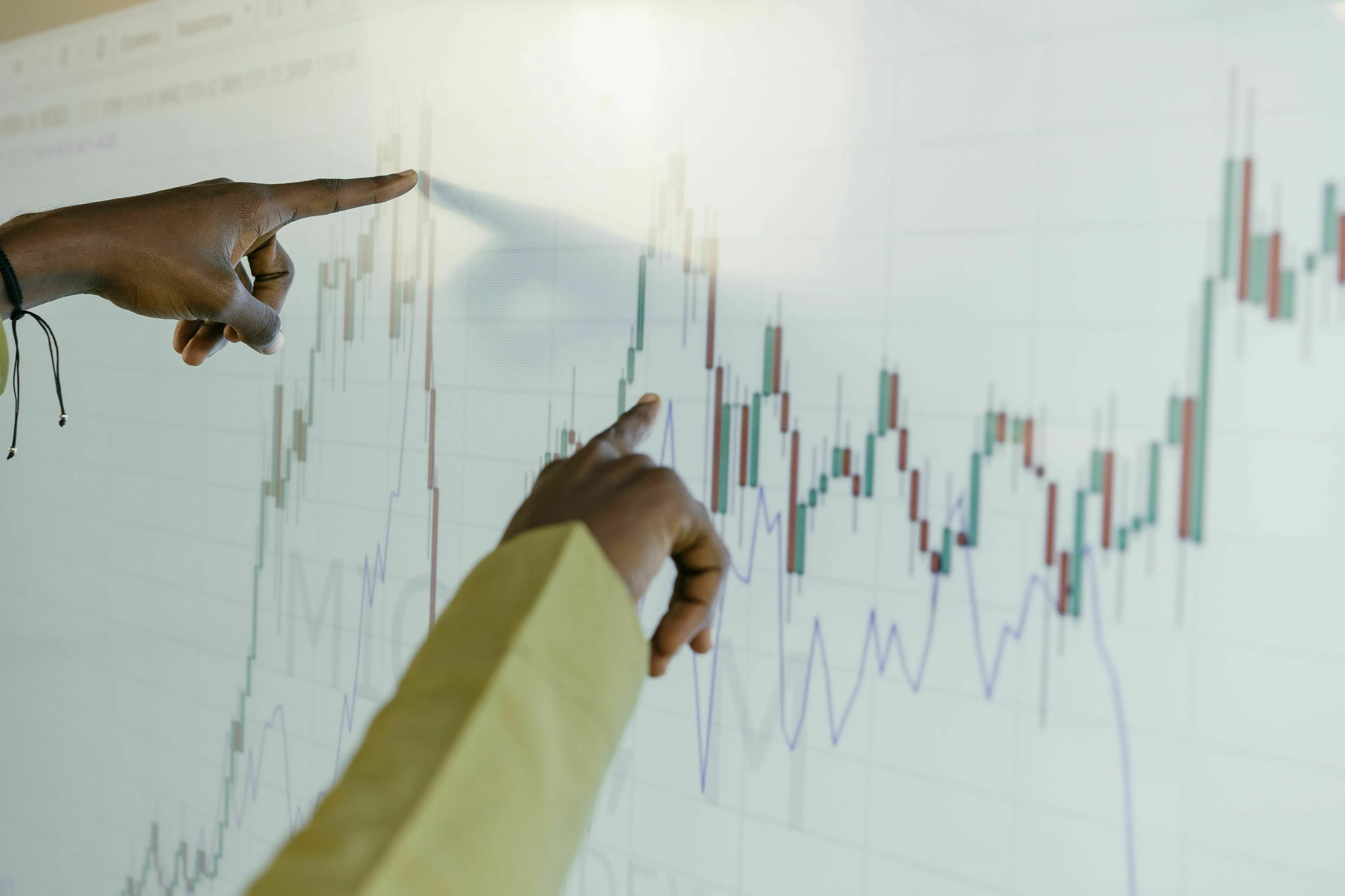Two hands pointing at a financial chart on a screen. Good general knowledge for high IQs.