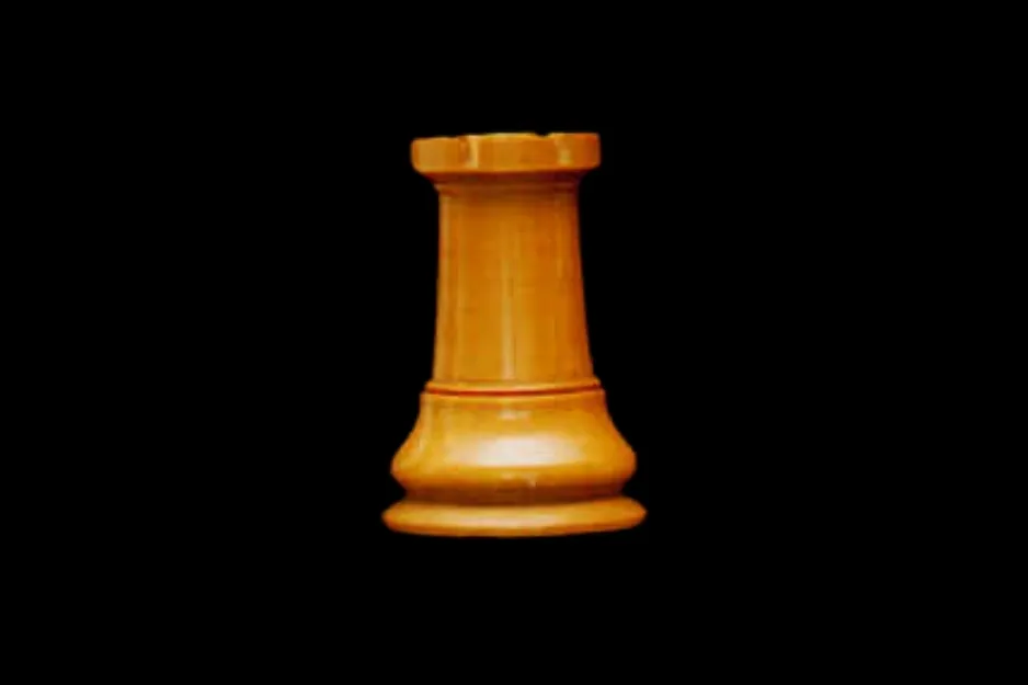 A light brown chess piece, a rook, stands vertically against a solid black background. This piece does not move diagonally.