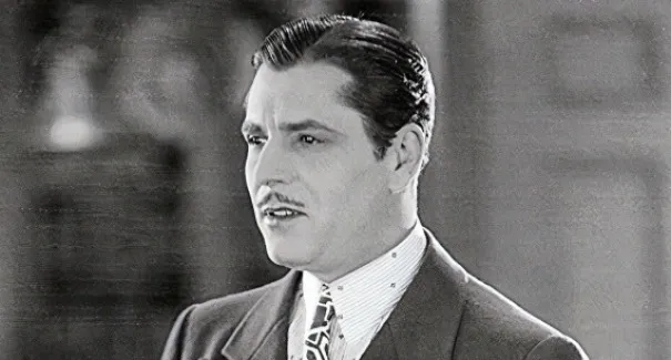 Black and white photo of a man in a suit with a mustache, embodying the character Jay Gatsby.