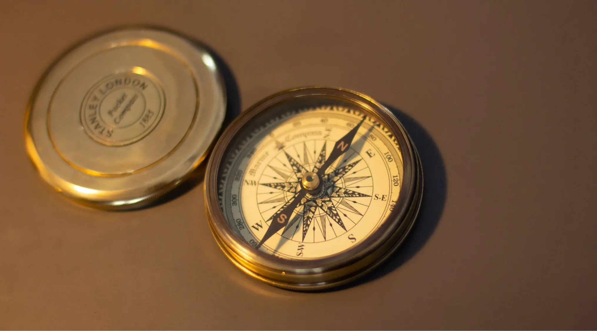 A gleaming brass compass and its lid rest on a surface, posing an Ultimate Science Quiz question about navigation.