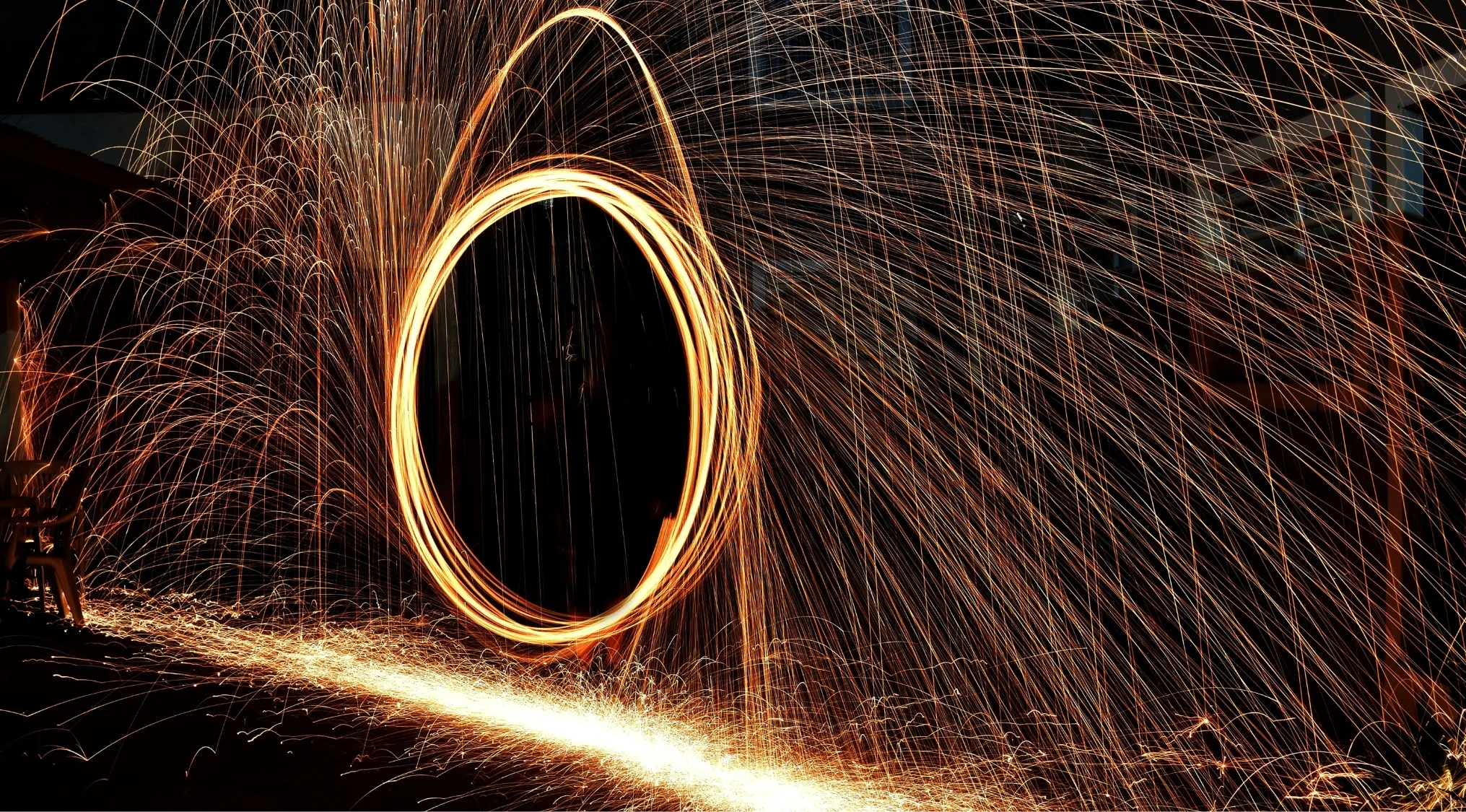 A long exposure shot of a glowing circular path of sparks with many trailing sparks, illustrating science quiz concepts.