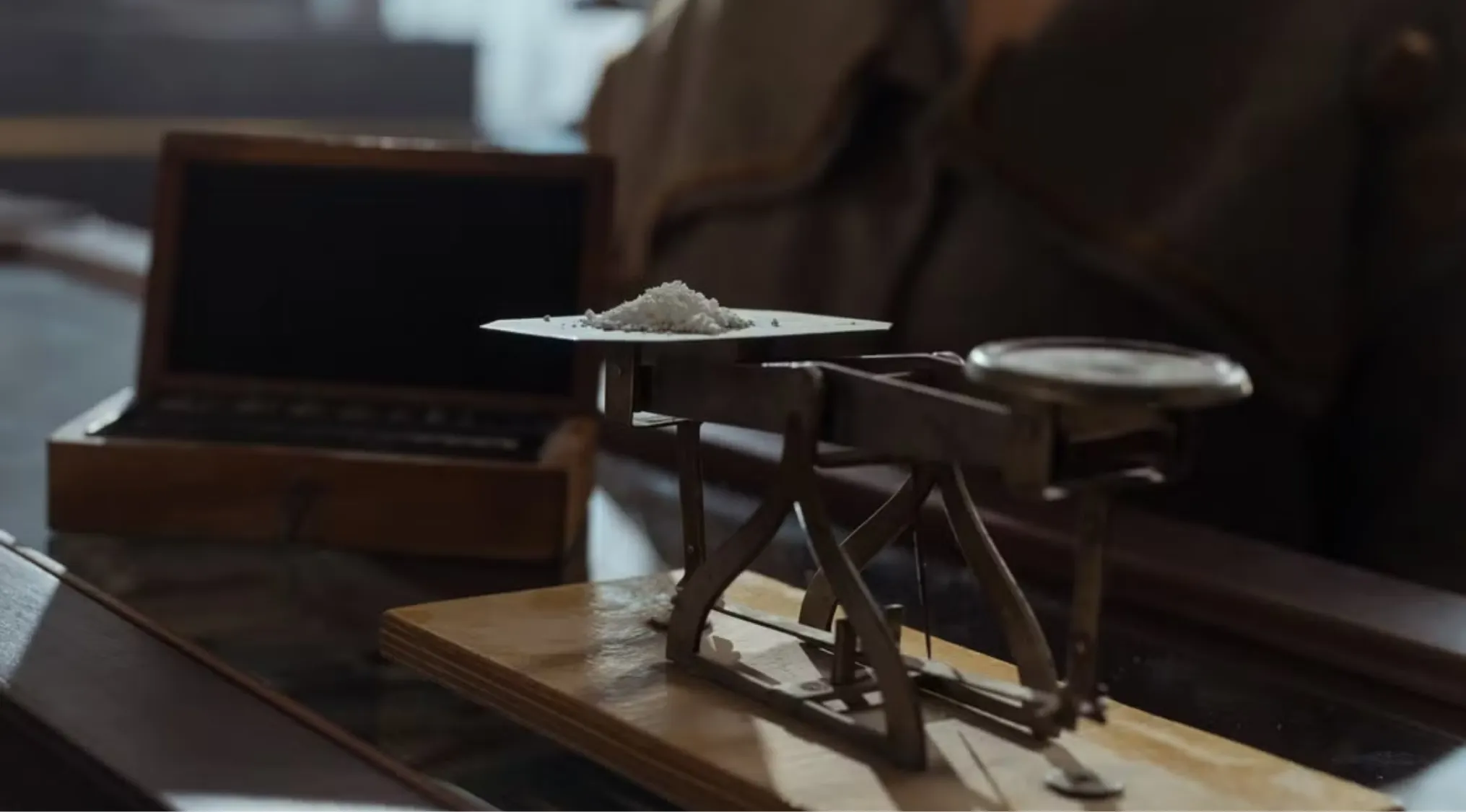 An antique balance scale holds a small pile of white powder, illustrating a science quiz concept on resistance to changes in motion.