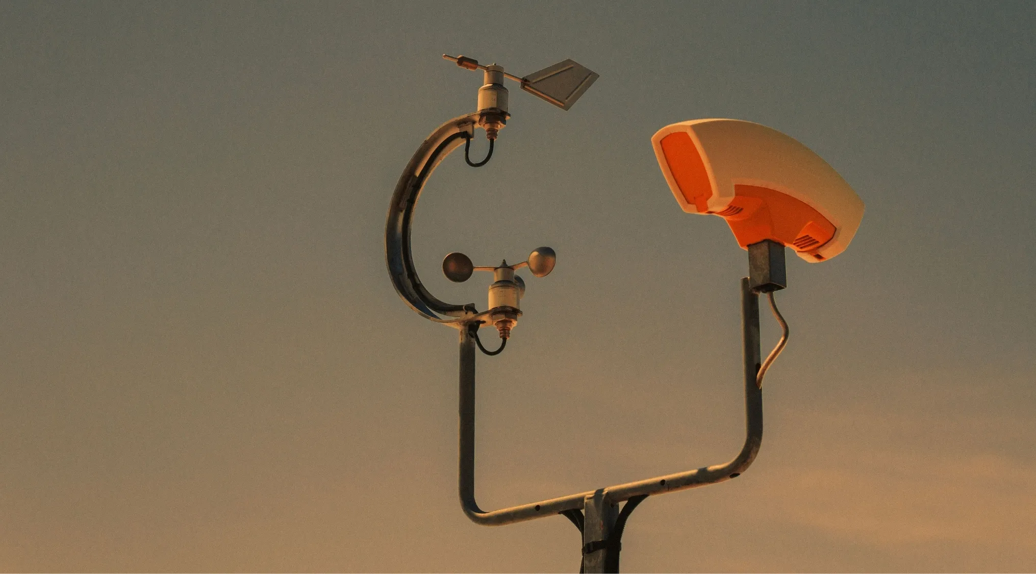 Anemometer and wind vane against a sky, devices measuring wind speed and direction for a science quiz.