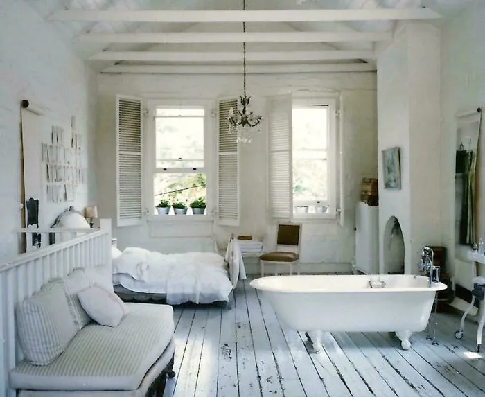 A rustic white bedroom with a claw-foot bathtub at the foot of the bed, a peculiar real estate listing.