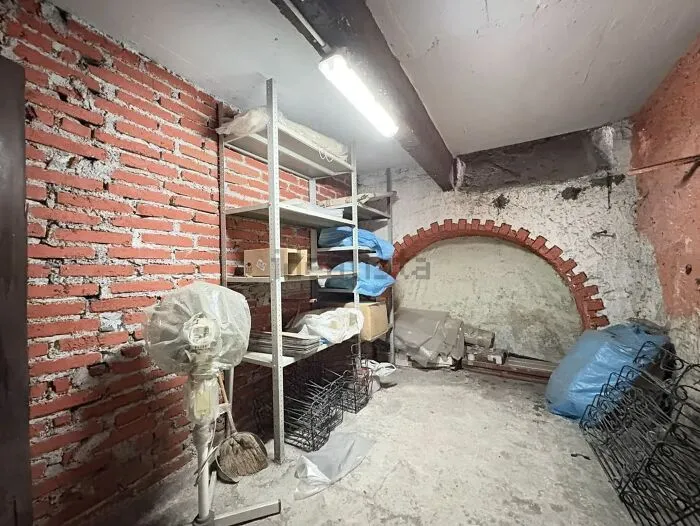 Unhinged real estate listing: a dimly lit, unfinished basement with exposed brick walls, metal shelving, and various stored items.