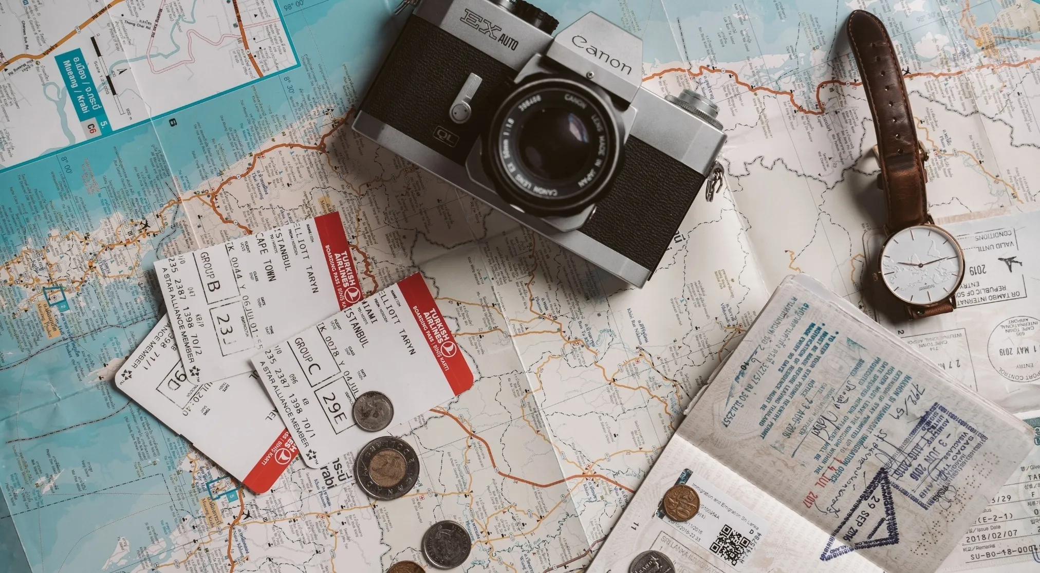 Travel planning with a map, vintage camera, watch, coins, flight tickets, and a passport. Always keep a copy of your travel documents when traveling internationally.