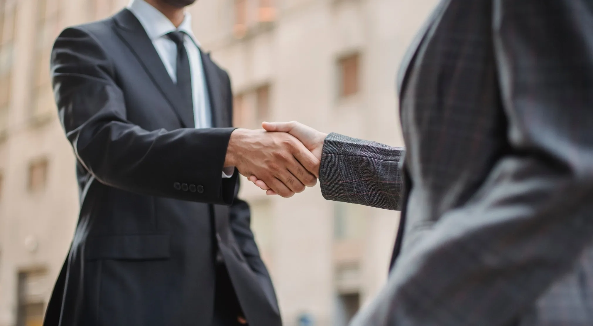 Two professionals in suits shaking hands. This image relates to when making introductions.