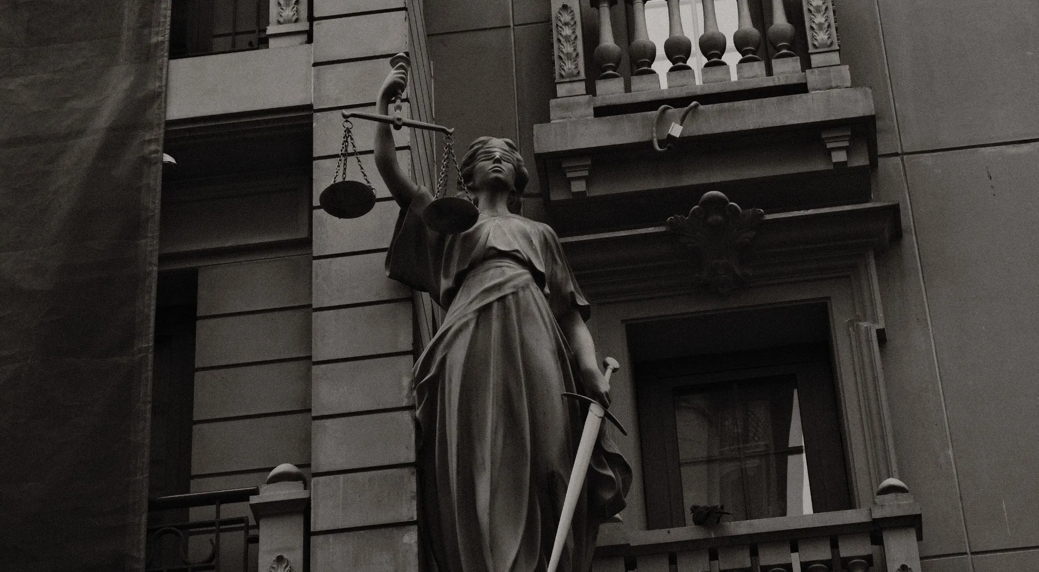 Lady Justice statue in black and white. Understand the difference between a will and a living trust.