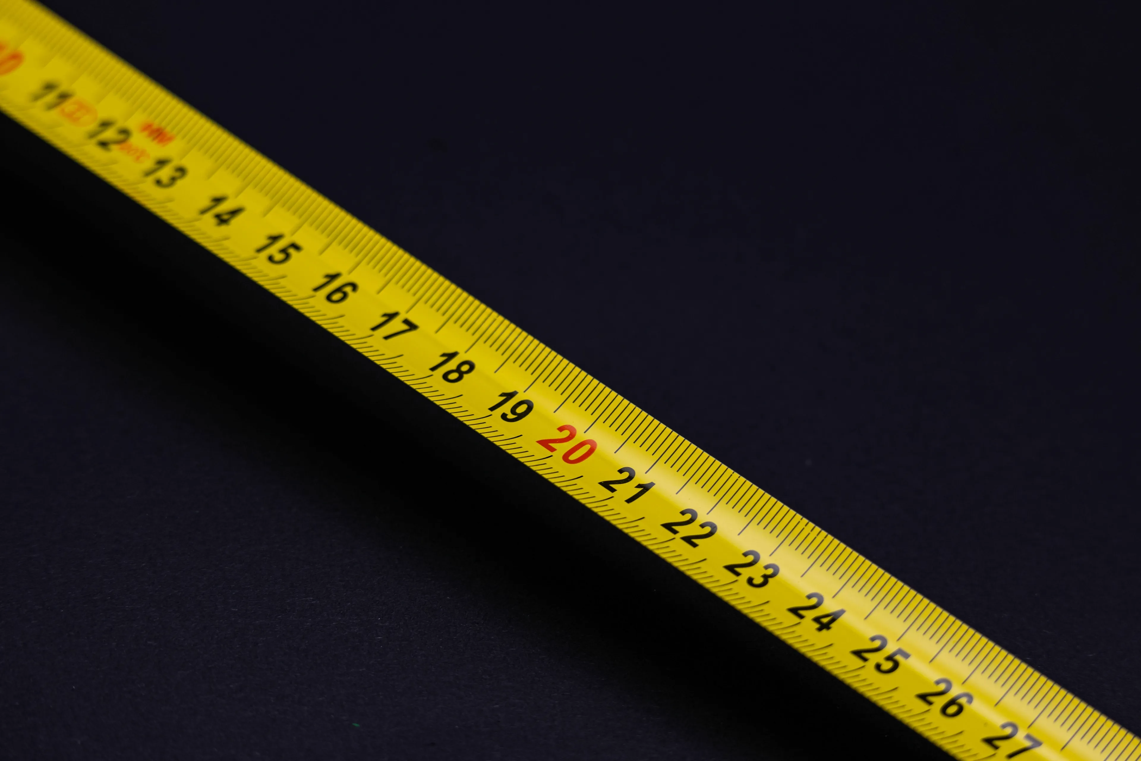 A yellow measuring tape laid diagonally against a dark background, showing centimeters for a general knowledge quiz.