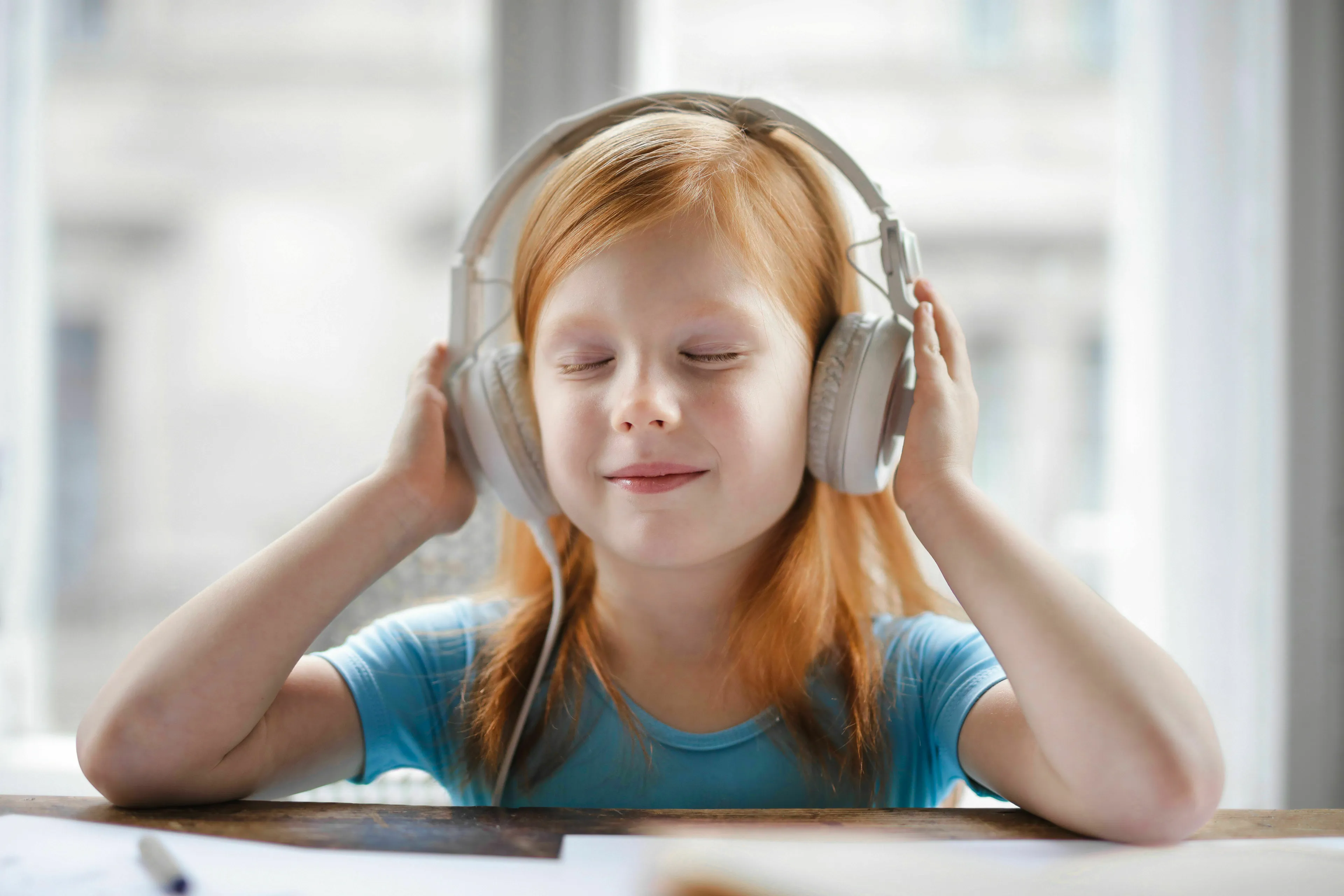 A young red-haired girl with closed eyes, enjoying music through headphones, for when feeling low and handling loneliness.
