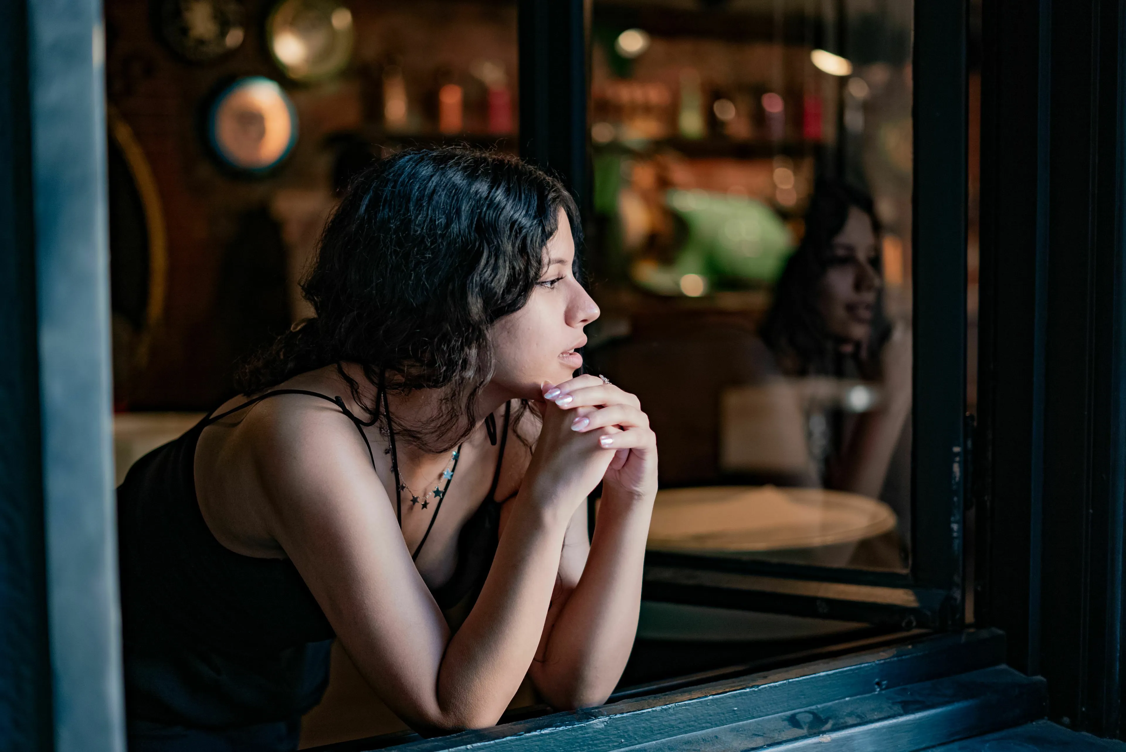 A thoughtful woman looking out a window, reflecting on handling loneliness and missing someone.