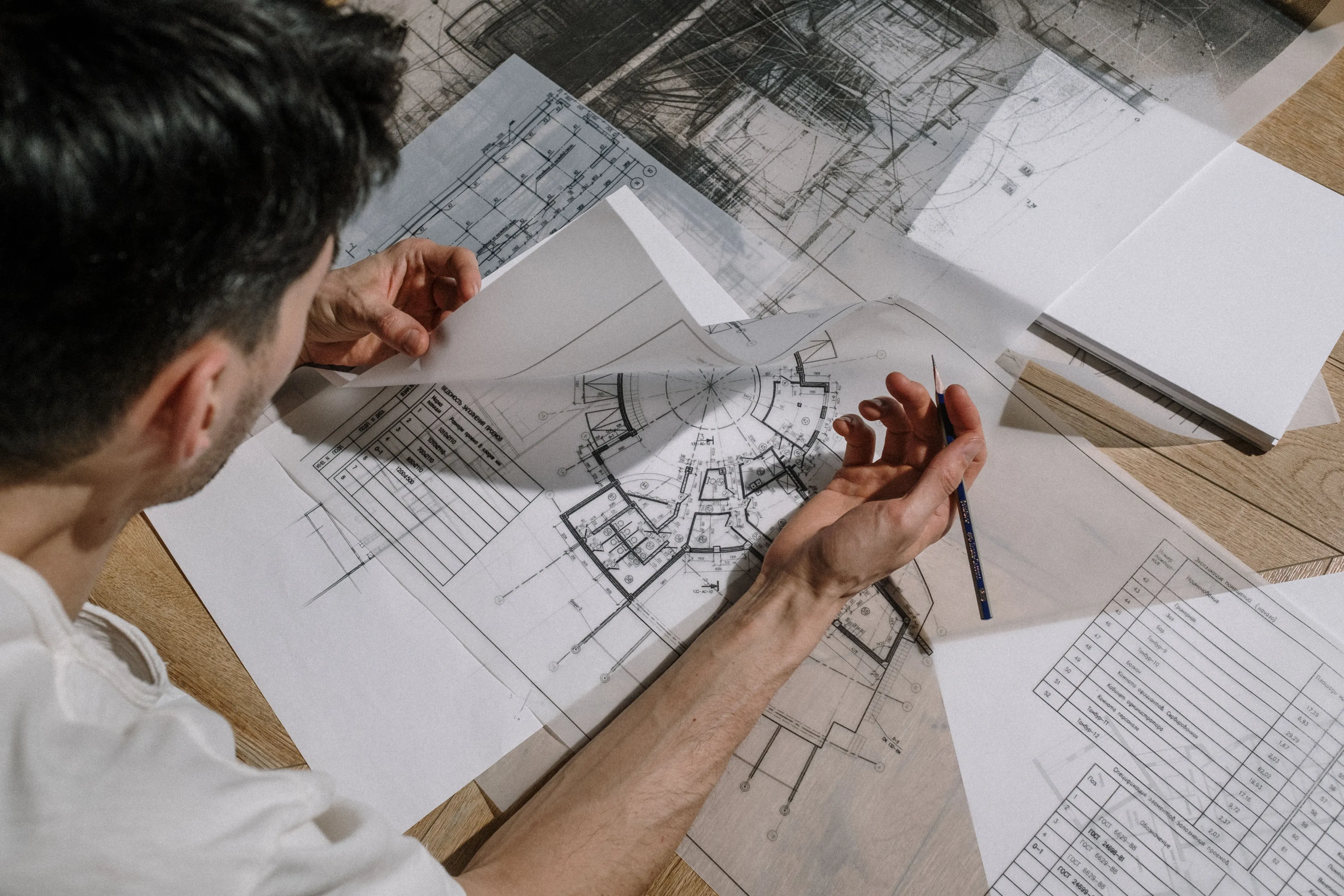 An overhead view of a master architect reviewing blueprints and architectural drawings at a desk, representing an ideal job.
