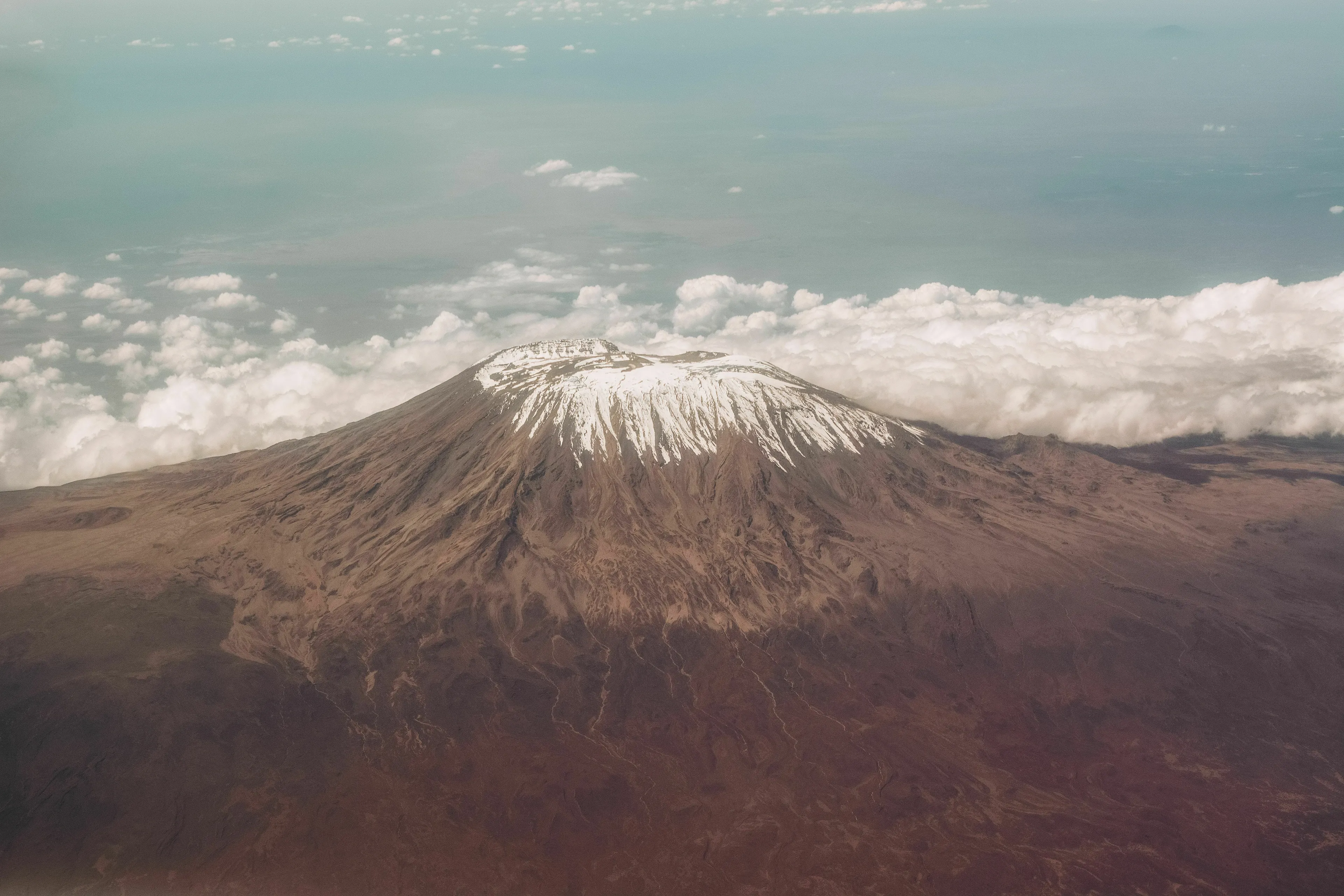 Mount Kilimanjaro, a snow-capped mountain, rises above the clouds in Tanzania.