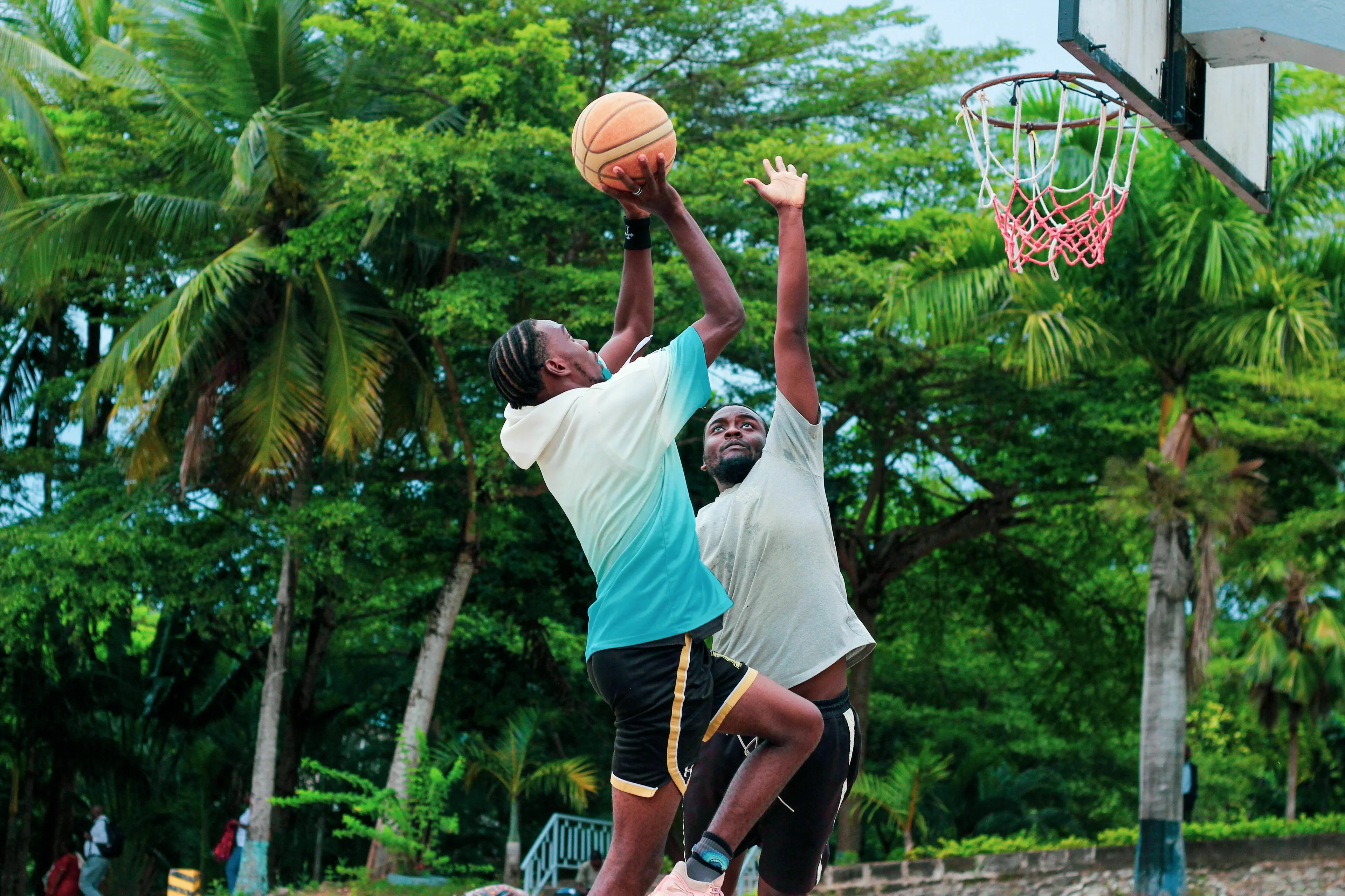 Two basketball players on the court, one shooting the ball towards the hoop.